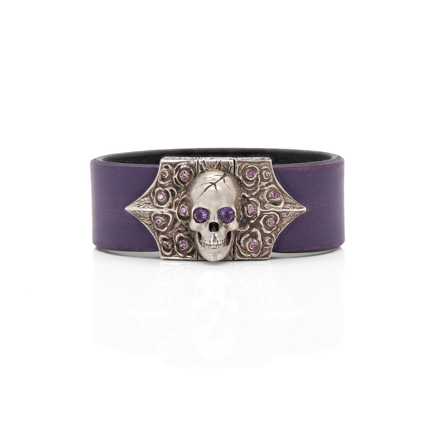 The Skull & Roses Bracelet is embellished with rose engravings set with pink sapphires. The amethyst eyes of the skull adds a special glare to the bracelet.
The bracelet is strapped by a violet leather strap, making it both stylish and comfortable