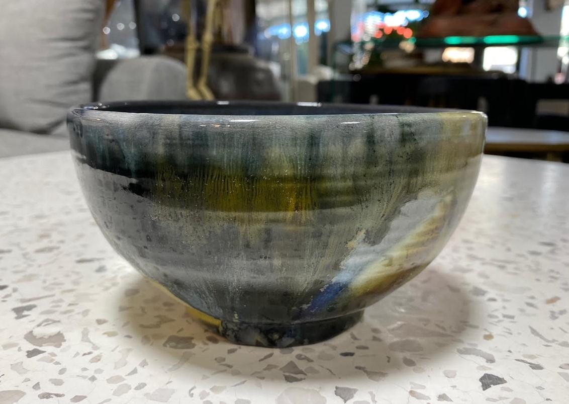 A beautiful and quite engaging relatively large Chawan tea bowl by famed Japanese Hawaiian American pottery master Toshiko Takaezu. The fired porcelain bowl features a vast array of shifting, vibrant, and colorful glazes (with earth tones of browns,