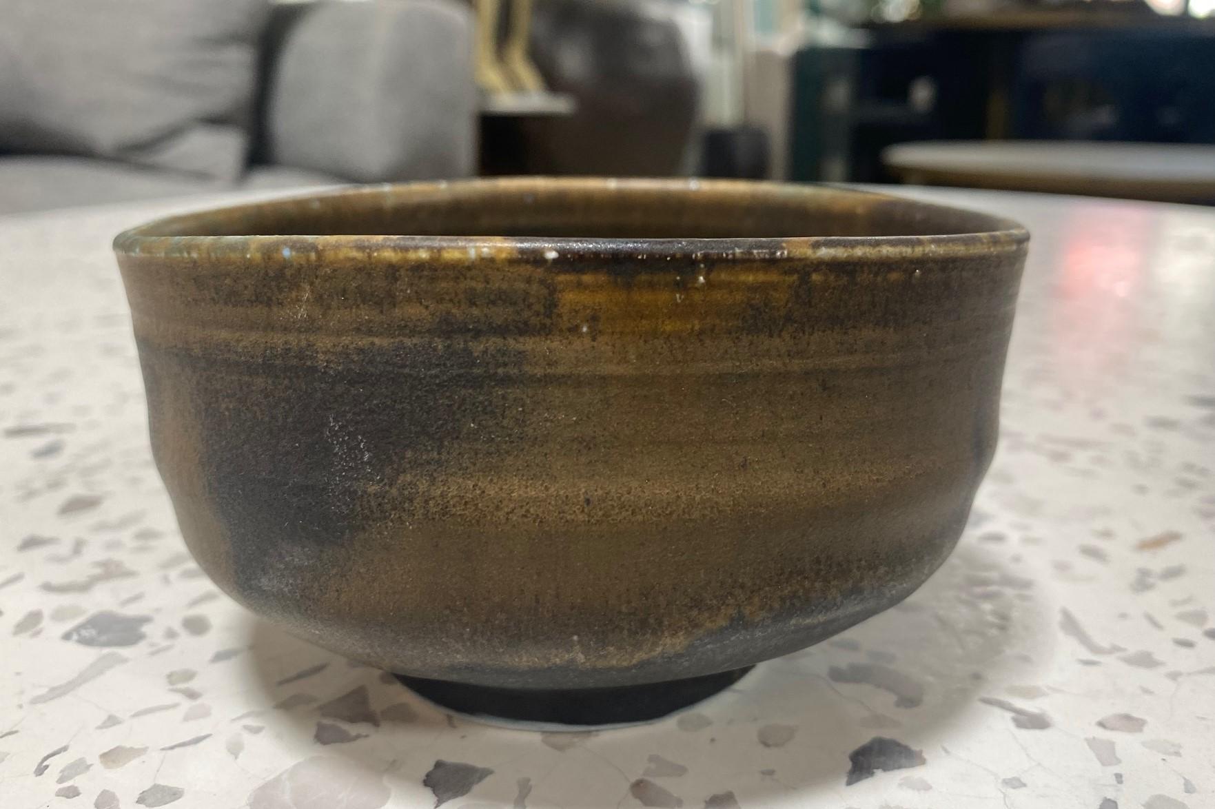 A beautiful and quite engaging sumptuously glazed Chawan tea bowl by famed Japanese Hawaiian American pottery master Toshiko Takaezu. The fired porcelain bowl features a vast array of dark-shifting, vibrant glazes (with muted earth tones of blacks,