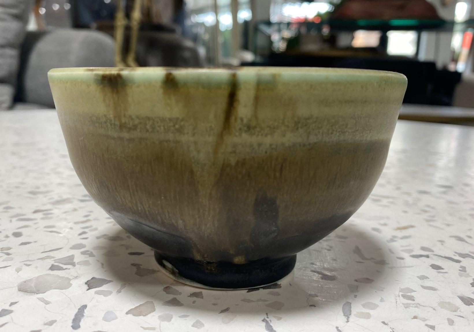 A beautiful and quite engaging Chawan tea bowl by famed Japanese Hawaiian American pottery master Toshiko Takaezu. The fired bowl features a vast array of shifting, vibrant, and colorful glazes (with earth tones of browns, greens,  black, greys, and