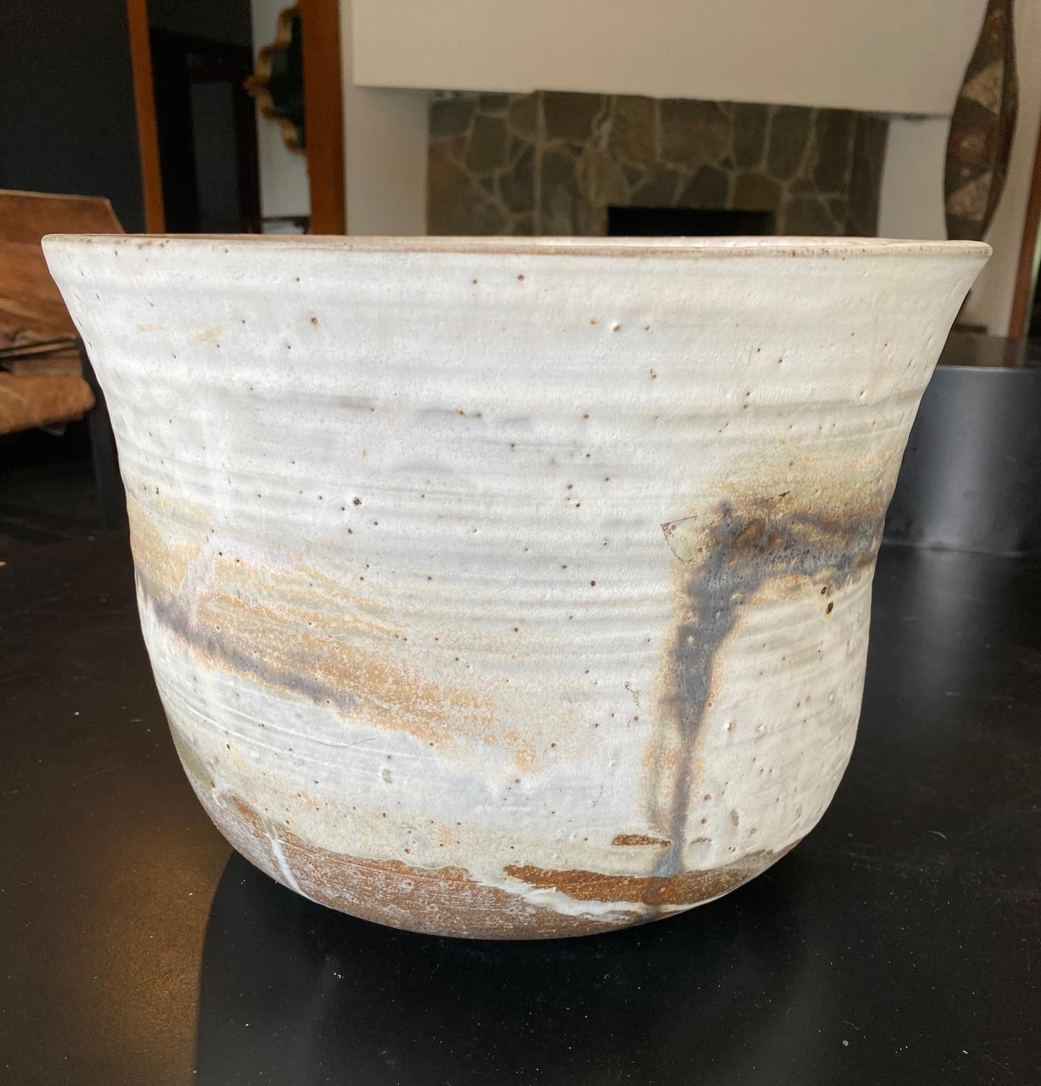 Una maceta/taza bastante grande, pesada y bellamente esmaltada del famoso maestro de la cerámica japonesa hawaiano-americana Toshiko Takaezu. La maceta de gres de alta cocción presenta una miríada de esmaltes goteados de tonos tierra cambiantes