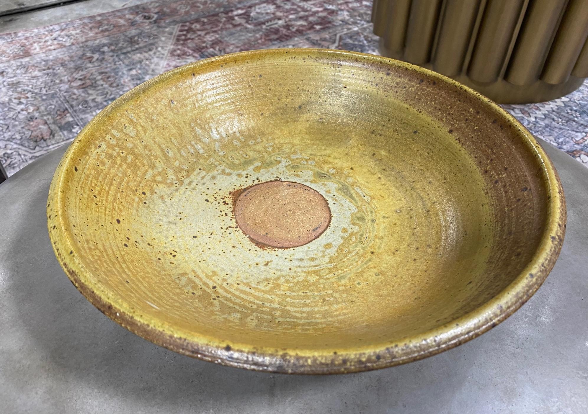 An absolutely gorgeous and wonderful large bowl by famed Japanese Hawaiian American pottery master Toshiko Takaezu. The quite large bowl features a unique design with wonderful browns and greens inter-mixed glazes. It is a unique and one-of-a-kind