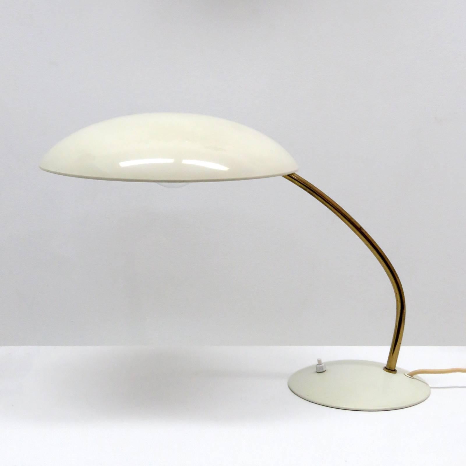 Original ivory enameled steel desk/ task lamps model '6782' by Christian Dell for Kaiser Idell, with a curved pivoting brass arm and a broad dome shade, marked.