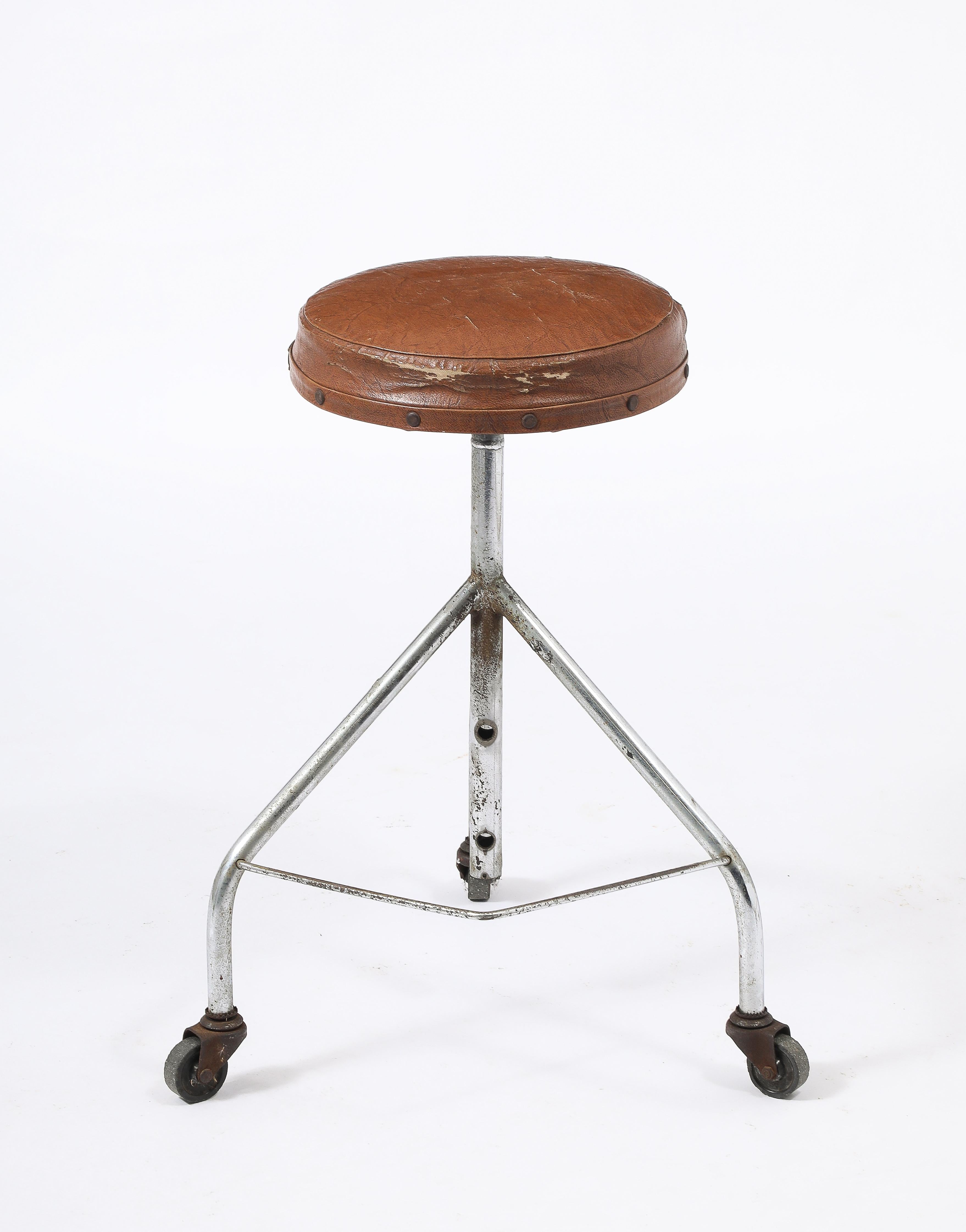 Industrial task stool on three casters, adjustable seat height and original moleskin upholstery.