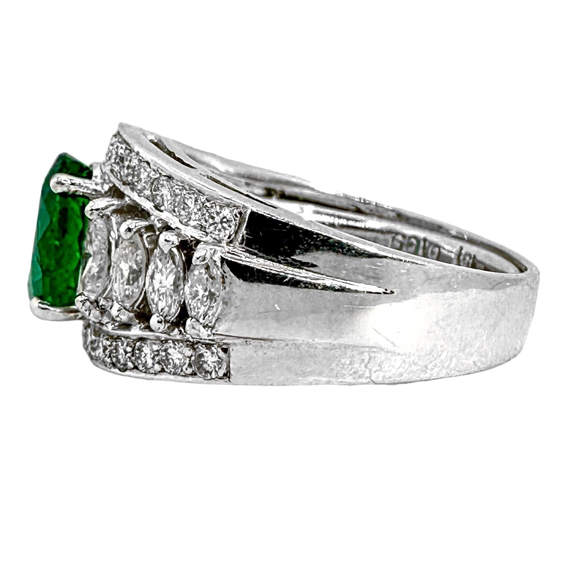 This elegant 18K white gold cocktail ring is set with one vivid green, oval shape, emerald in the center, flanked by eight marquise shape diamonds, and bordered on the top and bottom by twenty-six round brilliant cut diamonds. The effect is quite