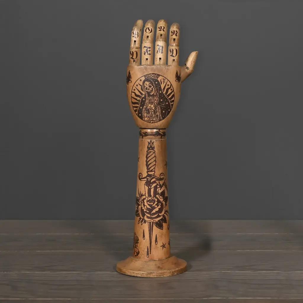 Bringen Sie Originalität und Kühnheit in Ihre Einrichtung mit diesem tätowierten Holzarm. Inspiriert von der alten und multikulturellen Kunst des Tätowierens ist jedes Stück mit kraftvollen und traumhaften Motiven verziert, die es zu einem