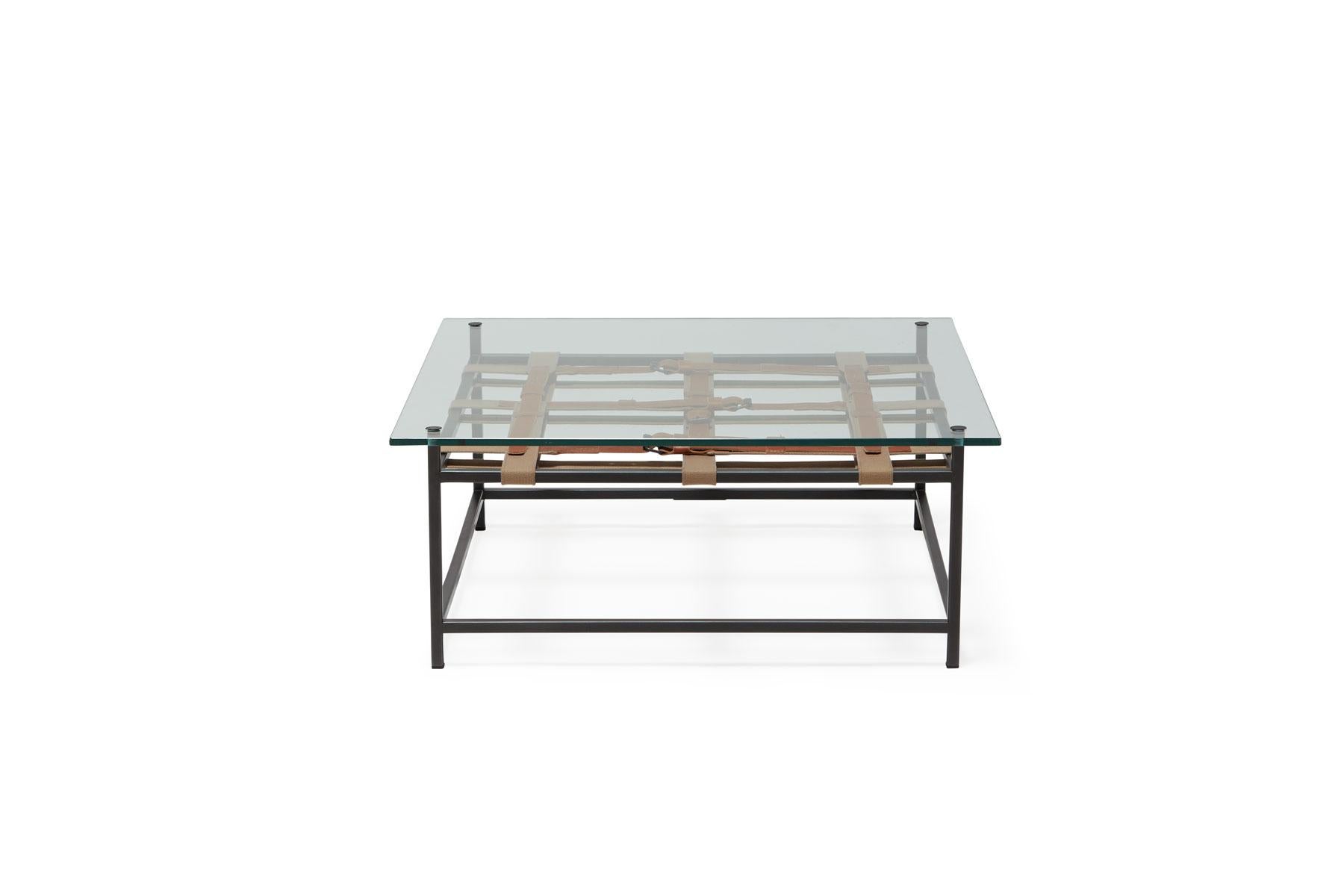 A glass topped coffee table that utilizes the signature Inheritance collection belts. The steel frame has a blackened steel finish and taupe cotton webbing belts with cognac leather and blackened steel buckles.

Every Stephen Kenn piece is made to