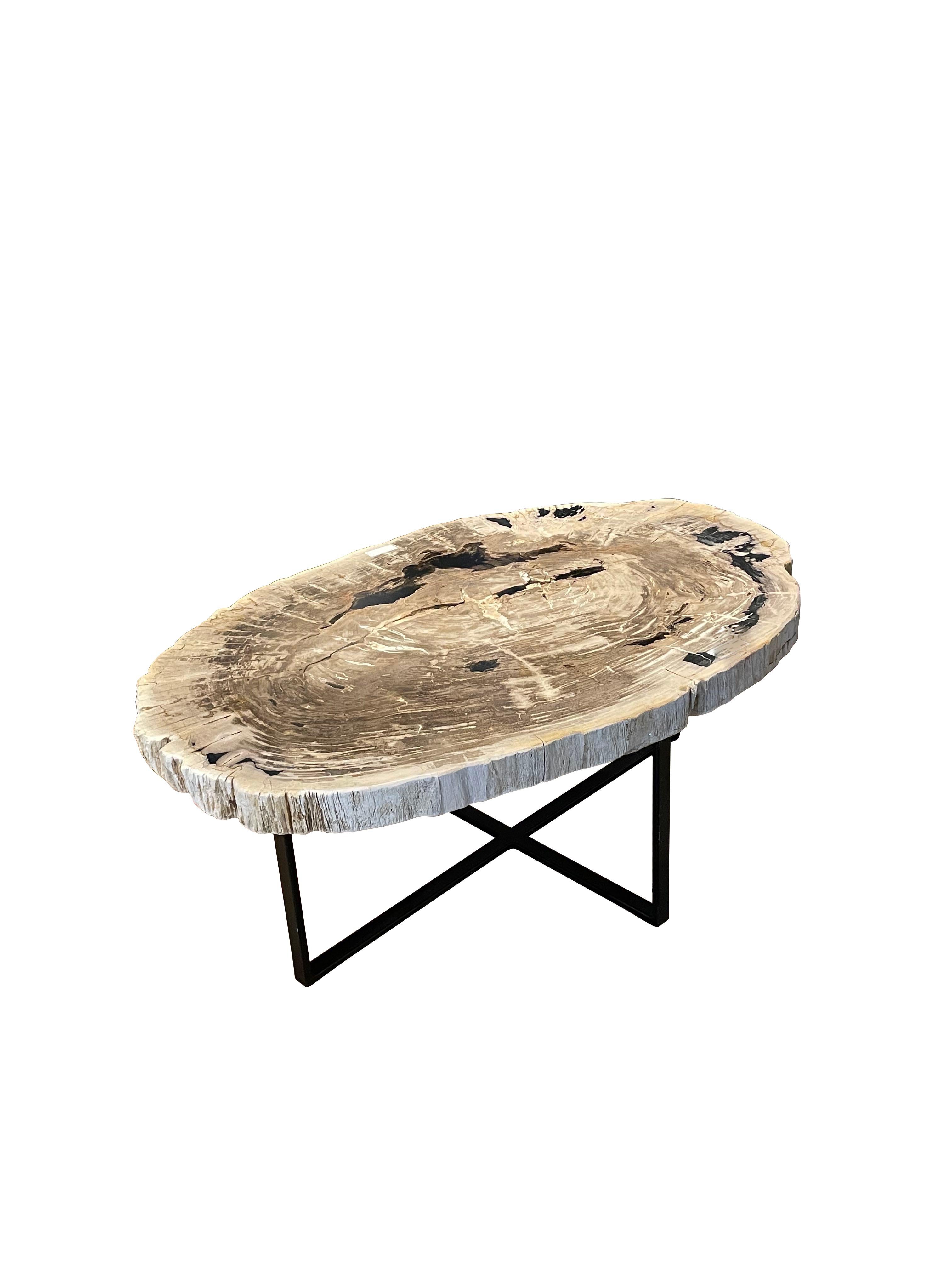 Tavolino contemporaneo indonesiano di grande spessore in legno pietrificato.
Supportato da una base in acciaio.
Top lucido color taupe, crema e nero.
I lati del piano a fette spesse sono color crema con una finitura strutturata.
