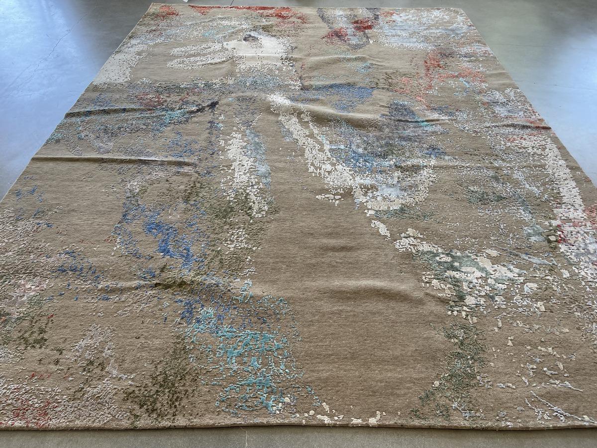 A neutral taupe base layer provides the canvas for an abstract swirl of blues, greens, coral and ivory. The result is a stunning contemporary area rug with color and texture. A combination of wool and viscose fibers makes for a rug both durable and