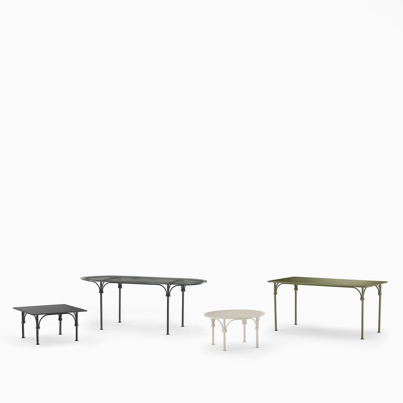 Femenina y luminosa, esta mesa de centro redonda de metal galvanizado es un complemento sublime para terrazas o patios refinados. Las juntas anulares acentúan el encuentro entre las patas aerodinámicas y los finos arcos que se extienden desde ellas,