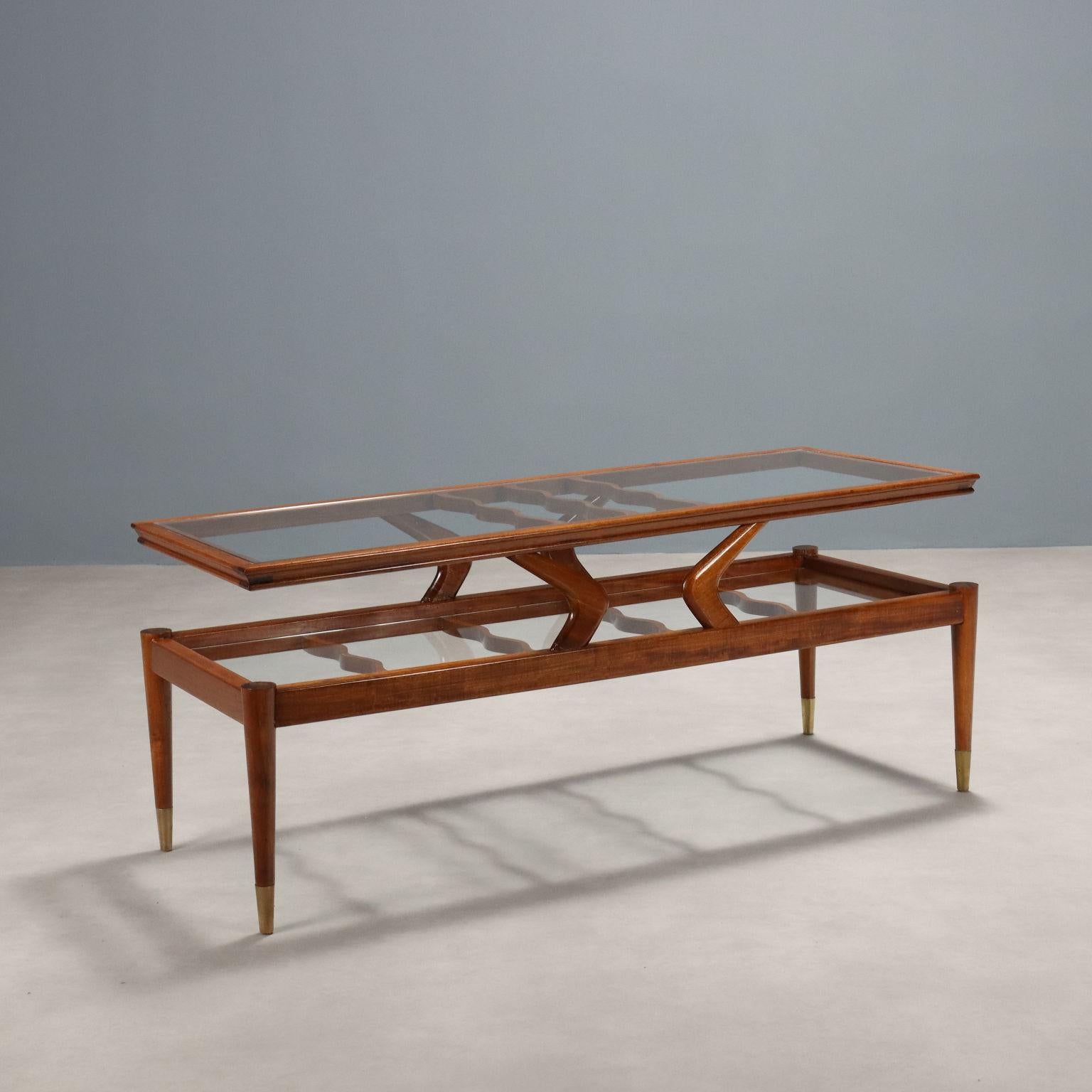 Elegante tavolino da centro di manifattura italiana in legno di teak con doppio ripiano in vetro di forma rettangolare con raccordi ondulati ed eleganti piedi in ottone.