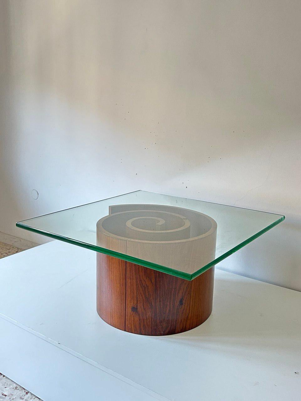 Splendido tavolo da caffè disegnato da Vladimir Kagan, la struttura si monta in 3 pezzi e forma una spirale in legno di noce, il vetro ha uno spessore di 2 cm. Presenta una piccola sbeccatura, su richiesta possiamo farla molare. 