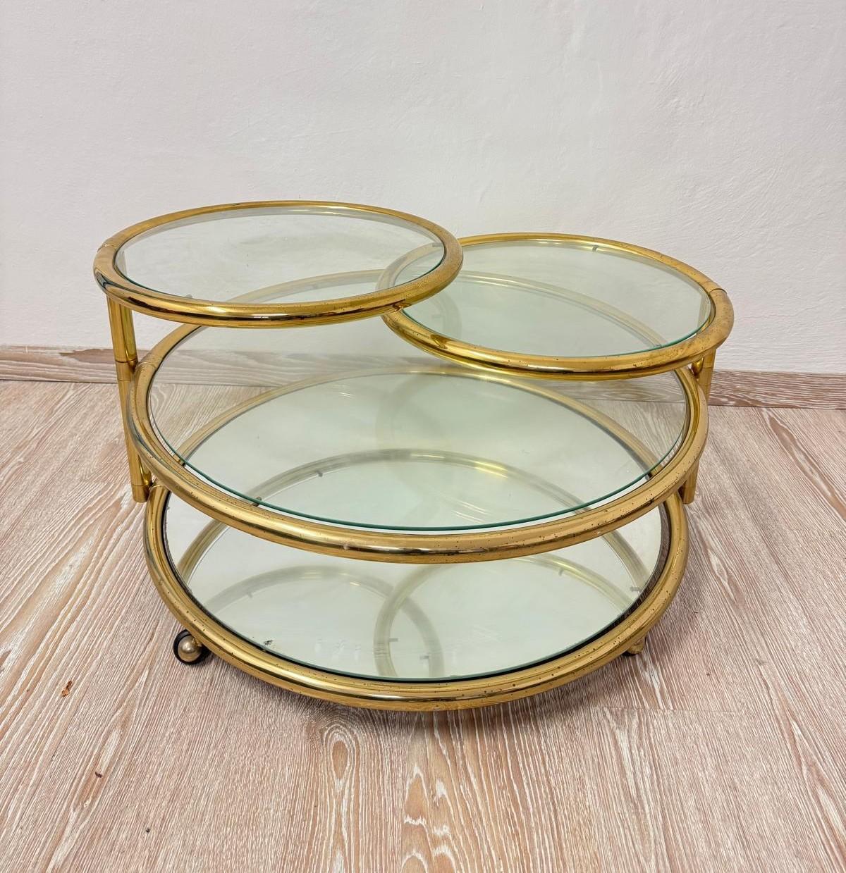 Couchtisch aus Glas und vergoldetem Metall. Besteht aus vier Glasscheiben, von denen die untere verspiegelt ist. Die beiden kleineren Gläser können um 360 Grad gedreht werden. Der Couchtisch ist in sehr gutem Zustand, er hat nur ein paar kleine