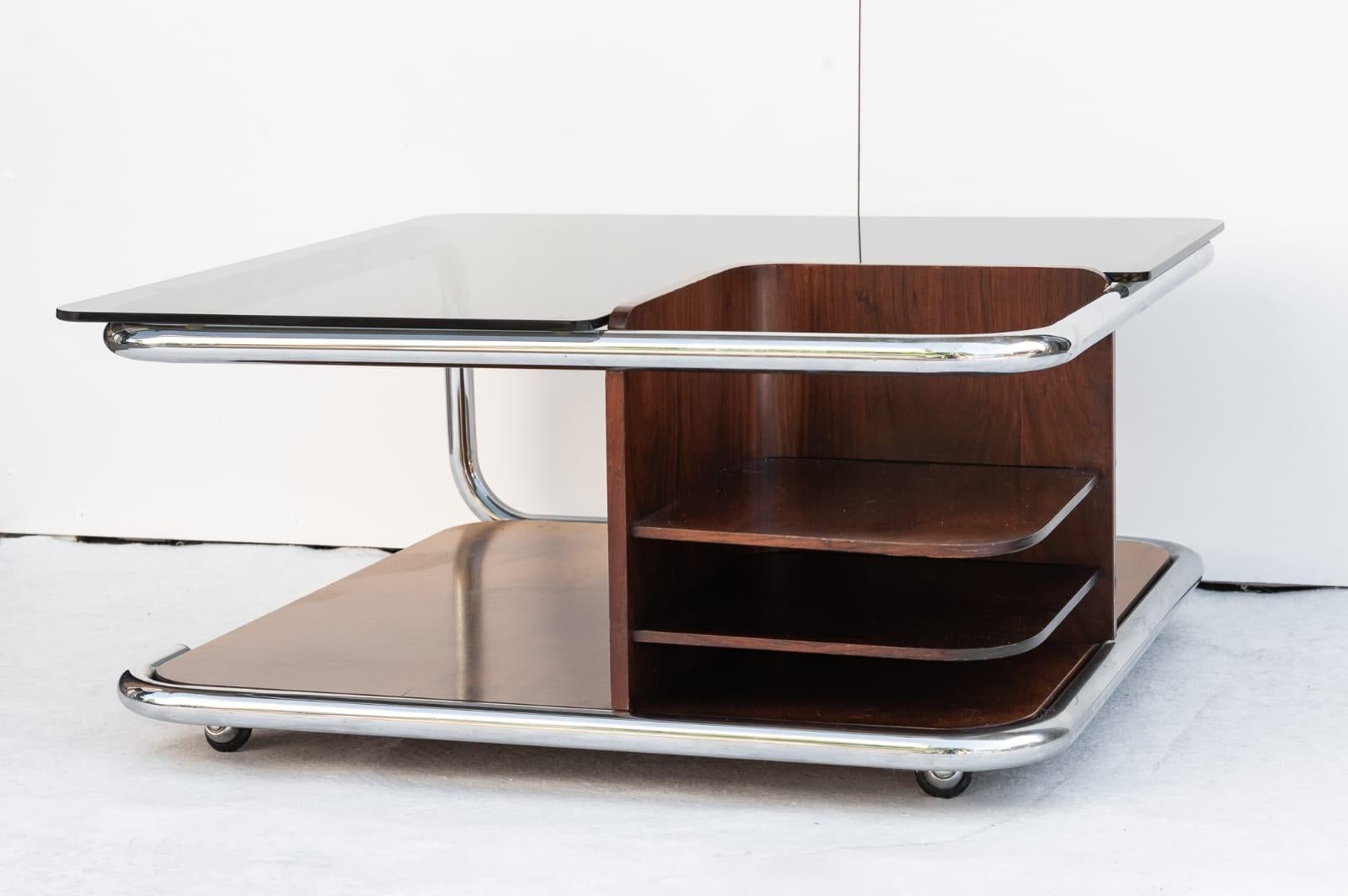 Tavolino da caffè in teak, Made in Italy, Anni '70. 
Particolare tavolino da caffè/salotto con ruote a sfera tipiche del periodo con portabottiglie. La struttura in teak con telaio in tubolare cromato che avvolge il perimetro del mobile. Il piano di