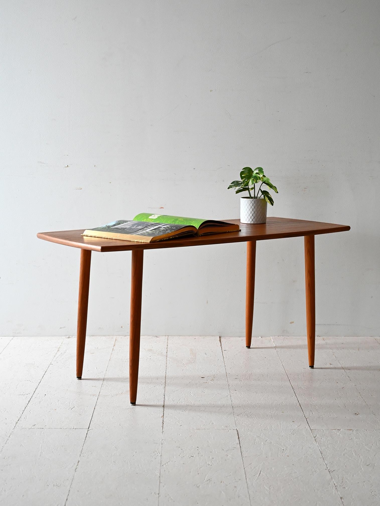 Vintage teak coffee table with tapered legs, Scandinavian production 1950s/60s. Slender profile and slim top.

Made in the 1950s/60s, this teak coffee table embodies the lightness and formal cleanliness of Scandinavian design. The thin, slightly