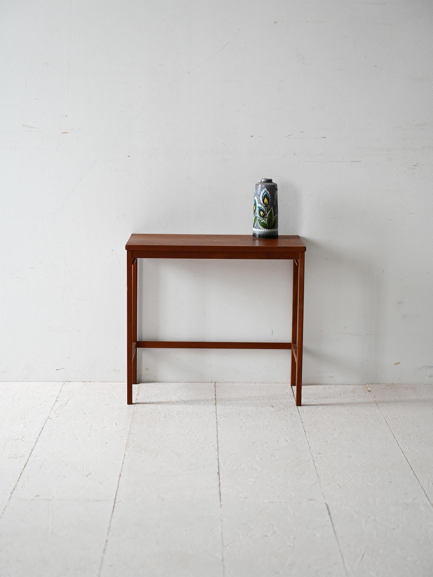 Scandinavian teak coffee table with lightweight frame and essential lines. Thin legs and lower crossbar

Scandinavian coffee table from the 1950s-60s, made of teak with a rectangular top with slender proportions. The structure features slender legs