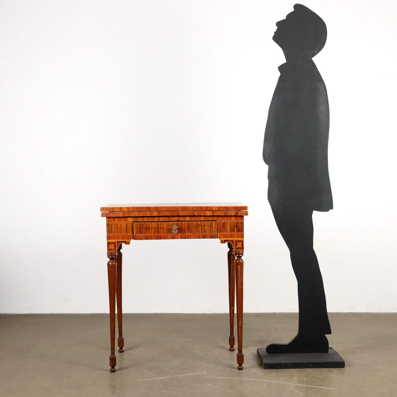 Small table attributable to the workshop of Giuseppe Colombo known as il Mortarino. Four elegantly turned and tapered walnut legs support a high band with drawer, subtended by small shelves with inlaid rosette; the entire surface is veneered in