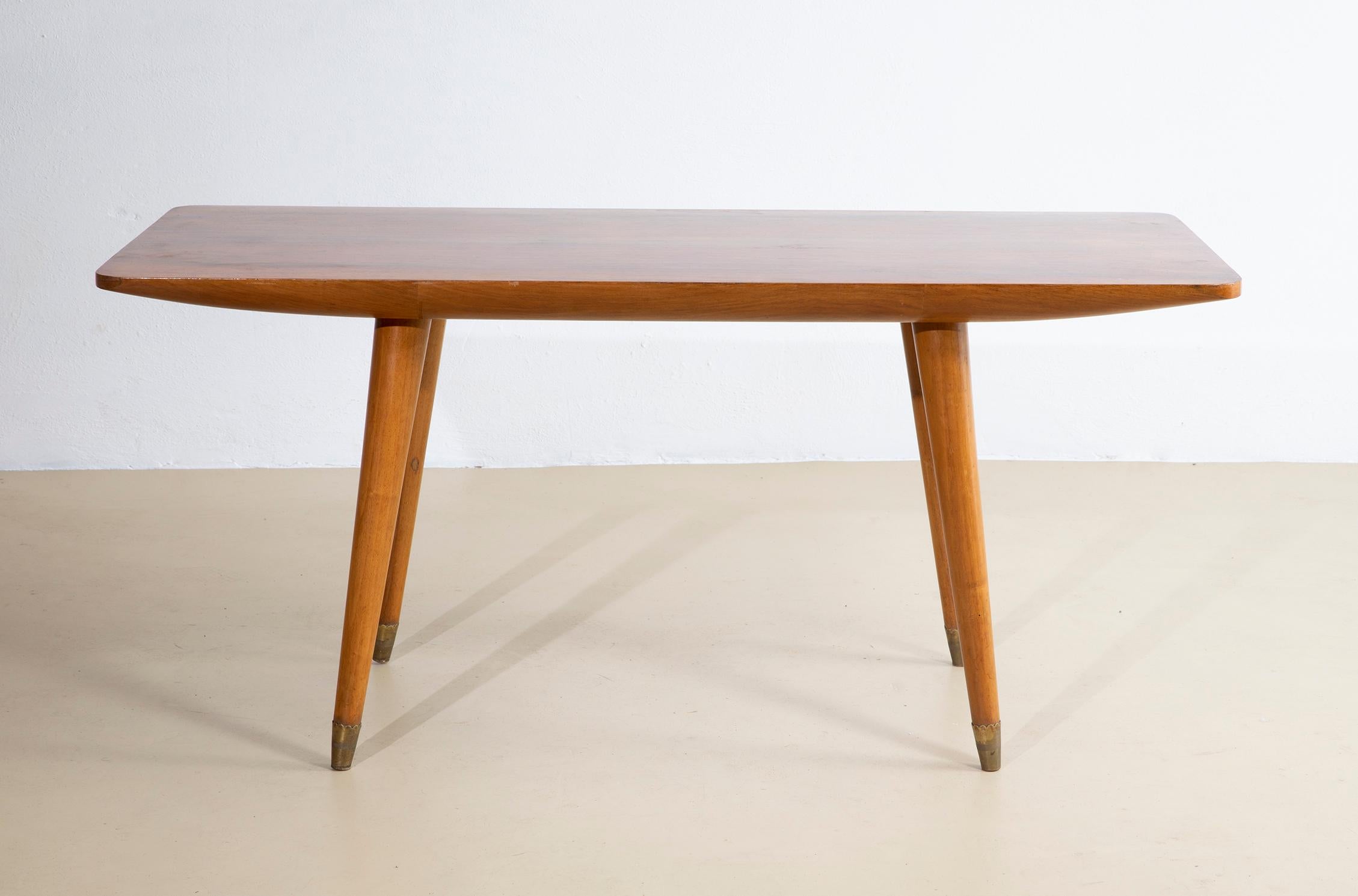 Mesa de centro italiana de madera de los años 50 especialmente bien hecha. La mesa de centro tiene un tablero rectangular con gruesas esquinas redondeadas que se estrecha hacia los extremos, chapado en nogal con una hermosa veta. Las patas son