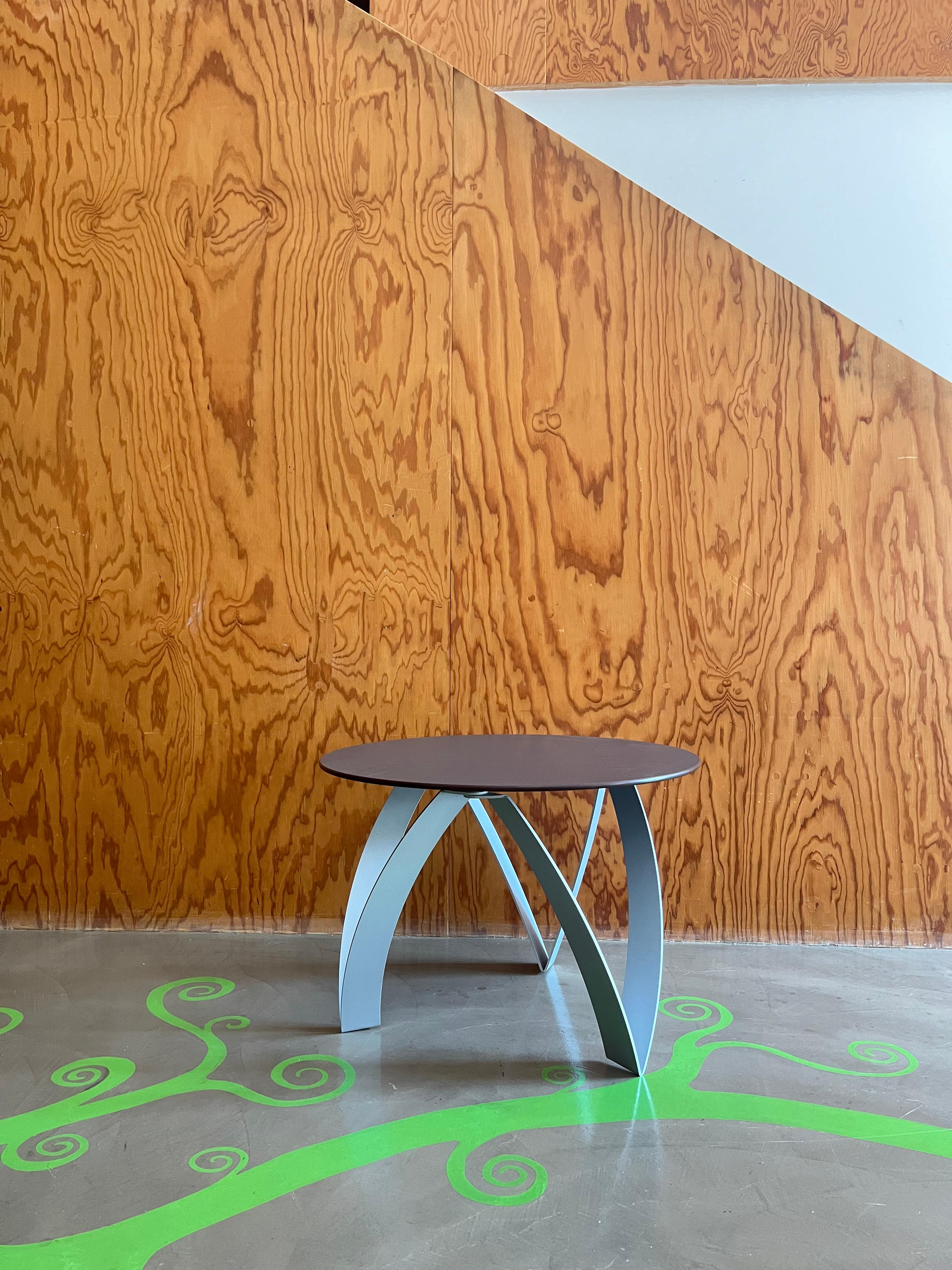 Origineller Couchtisch mit Platte aus grauem Schichtholz und silberfarbenen Aluminiumbeinen. Der Tisch heißt Kioko, wurde 1994 von Gionathan De Pas, Donato d'Urbino und Paolo Lomazzi, einem großen italienischen Designertrio, entworfen und von der