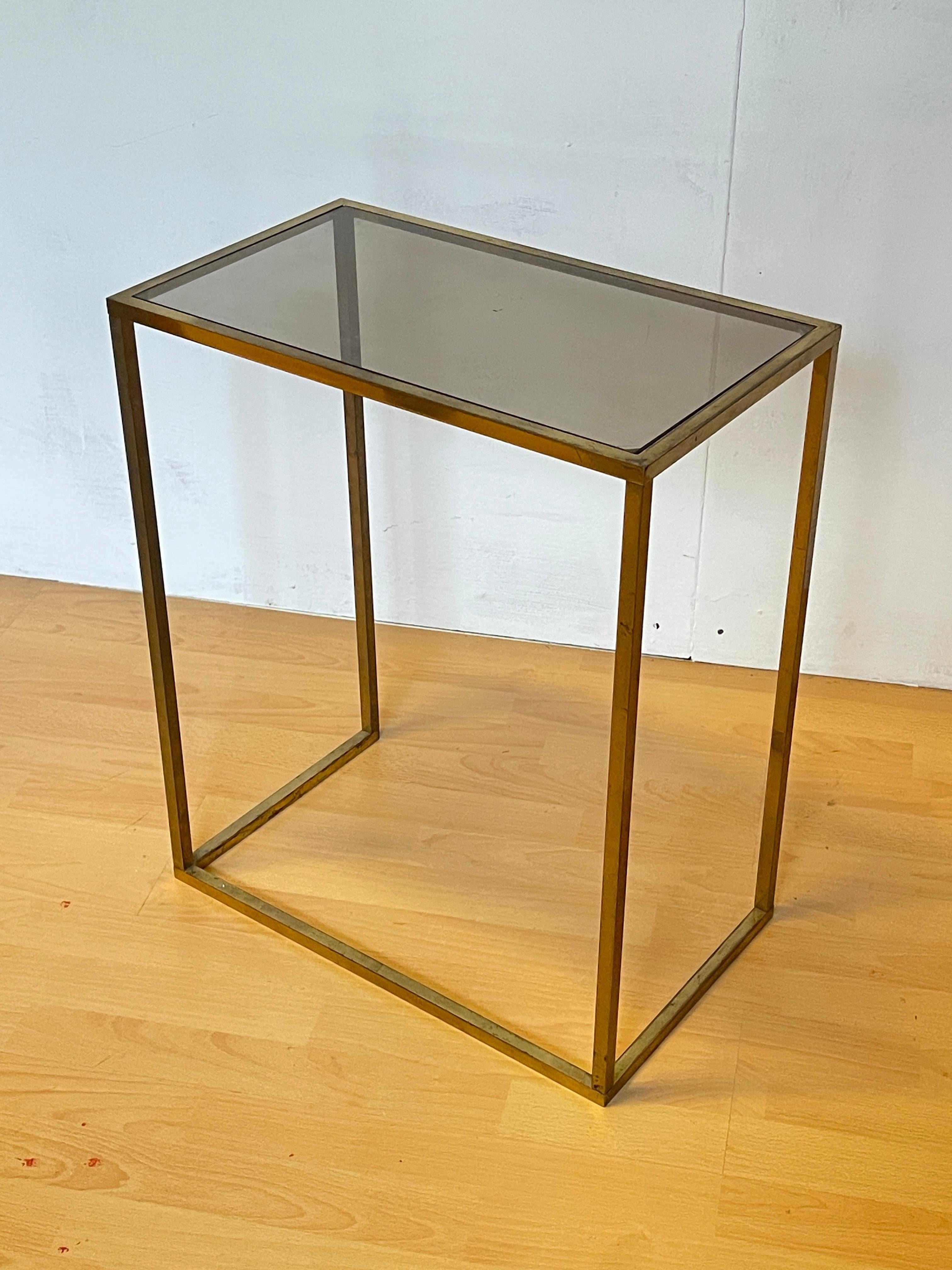 Elegante tavolino in ottone e vetro è il perfetto equilibrio tra stile contemporaneo e raffinatezza. La struttura geometrica in metallo con finitura dorata dona un tocco di luce e modernità, mentre il piano in vetro temperato fumé conferisce