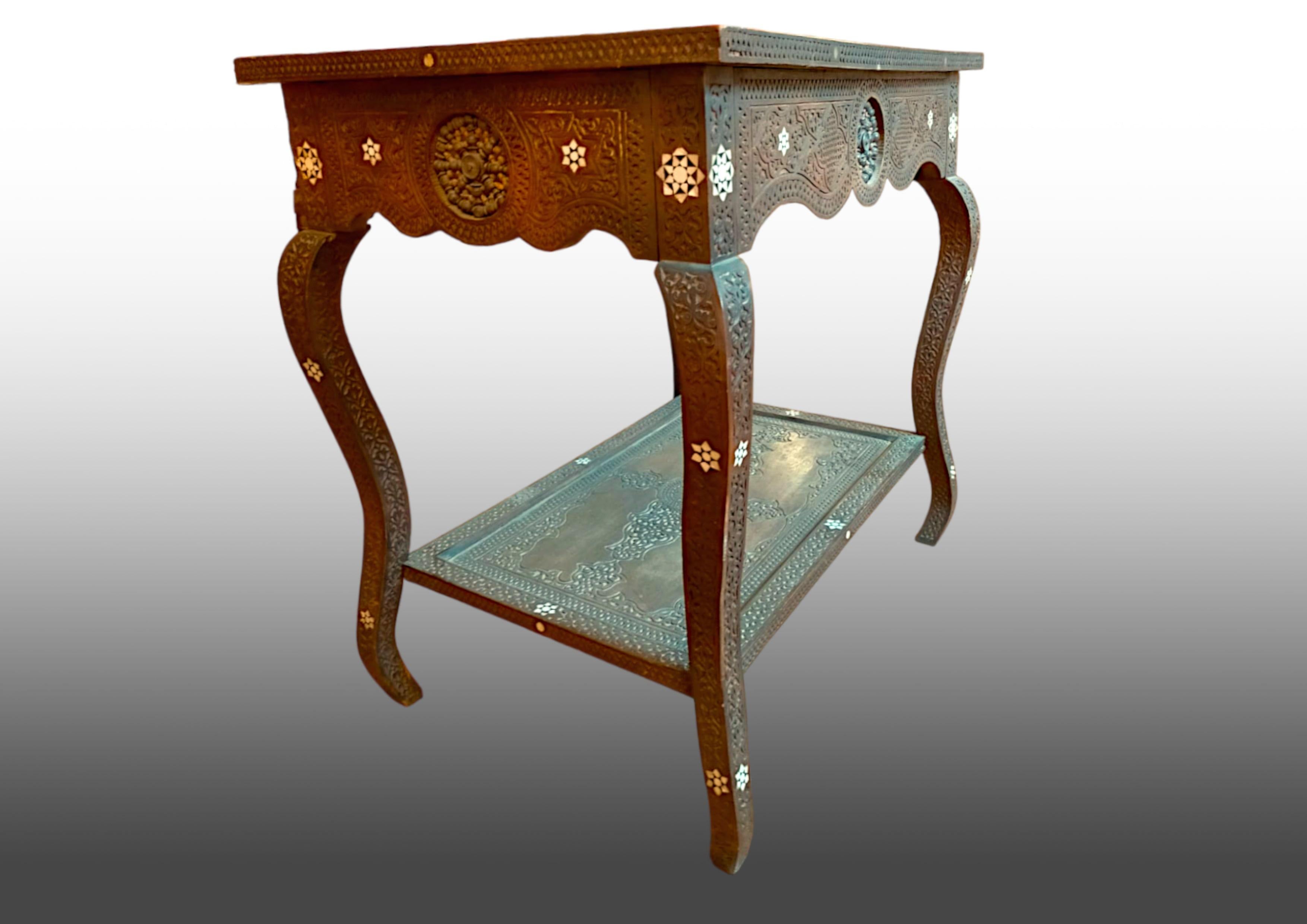 Table basse ancienne en bois sculpté indien, entièrement décorée de sculptures en bas-relief et de décorations en nacre.

Sur les bandes, 4 rosettes décoratives composées de petits éléments tournés.
Il est doté d'un double plateau et de quatre