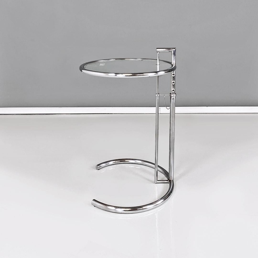 Tavolino regolabile modello E 1027, in acciaio cromato e vetro, del periodo moderno, progettato da Eileen Gray negli anni Novanta.
Tavolo da caffè regolabile modello E 1027, con struttura a base tonda in tubolare d'acciaio cromato lucido, con piano