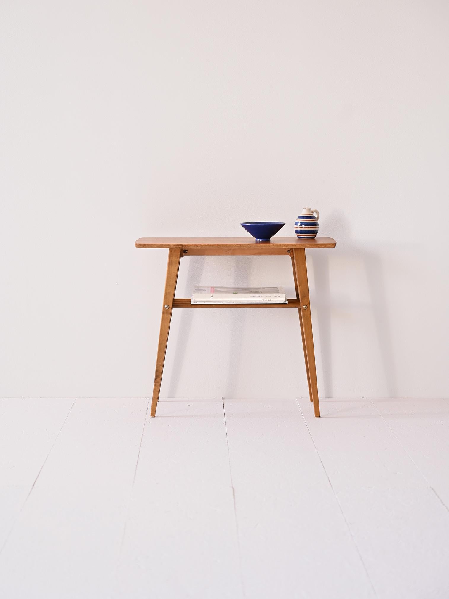 Un tavolino vintage con piano in teak e gambe in betulla, si distingue per il suo design elegante e funzionale. Il piano, realizzato in teak, è caratterizzato da una superficie calda e ricca che conferisce al tavolino un aspetto raffinato e