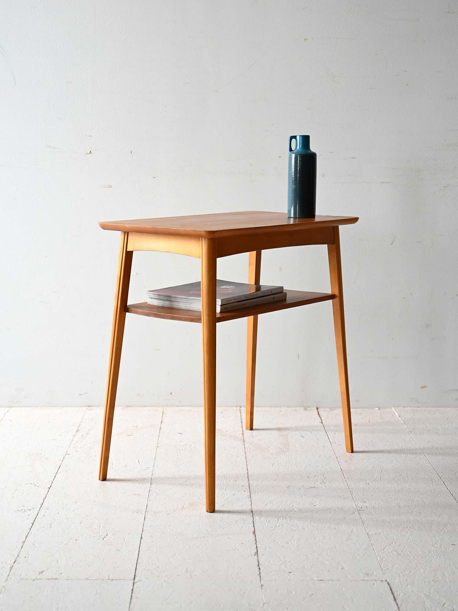 Vintage solid pine coffee table, 1960s, with built-in magazine shelf and tapered profiles.

Original Scandinavian coffee table from the 1960s, made of solid pine with a light finish and visible grain. The top features rounded corners and a slim