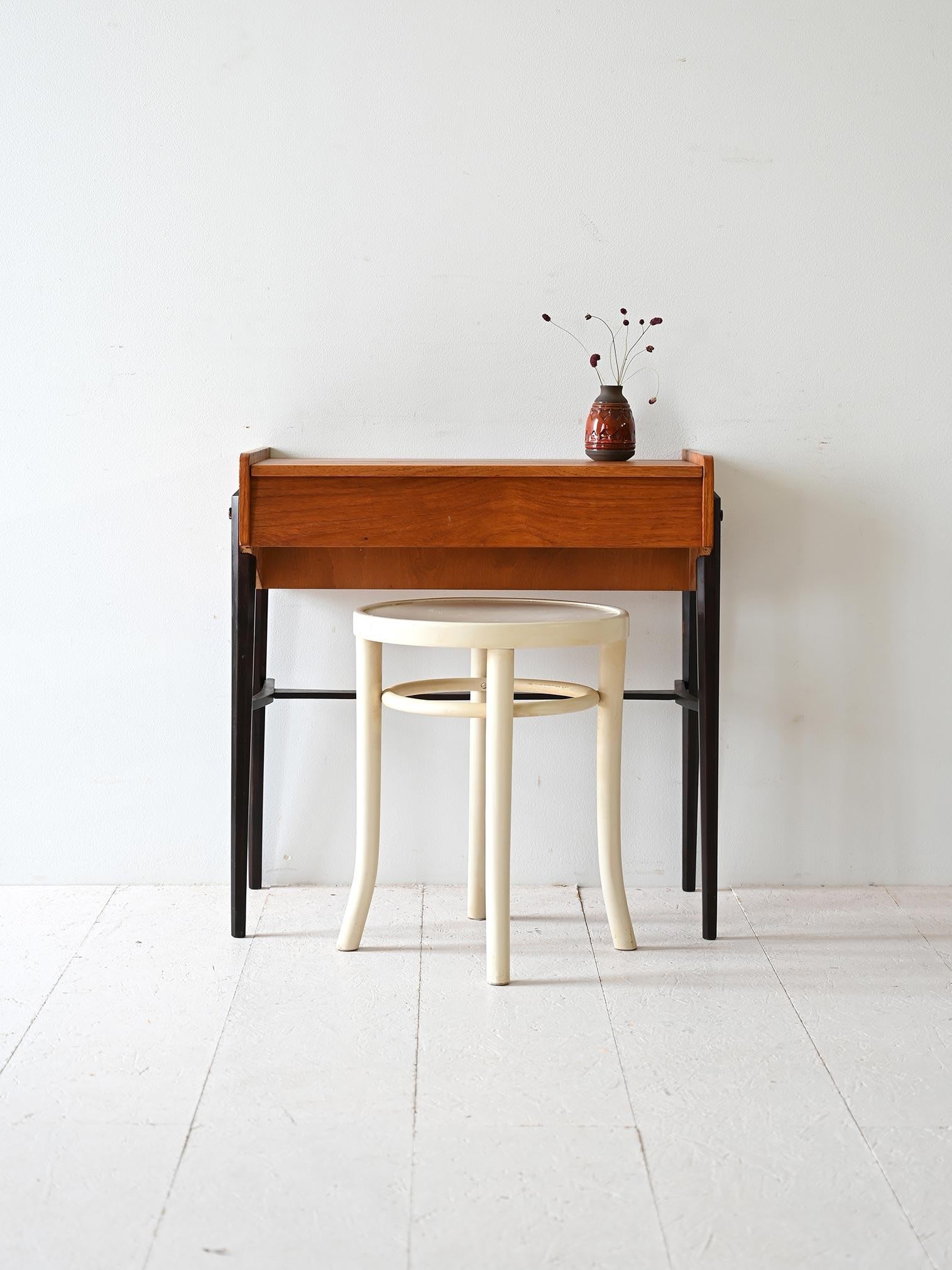 Original vintage table with a lift-up top that conceals a compartment for storing small items. The wood legs are painted black. 

Ideal as an entryway cabinet but also as a small corner for working on a PC. 
Good conditions. Potrebbe presentare dei