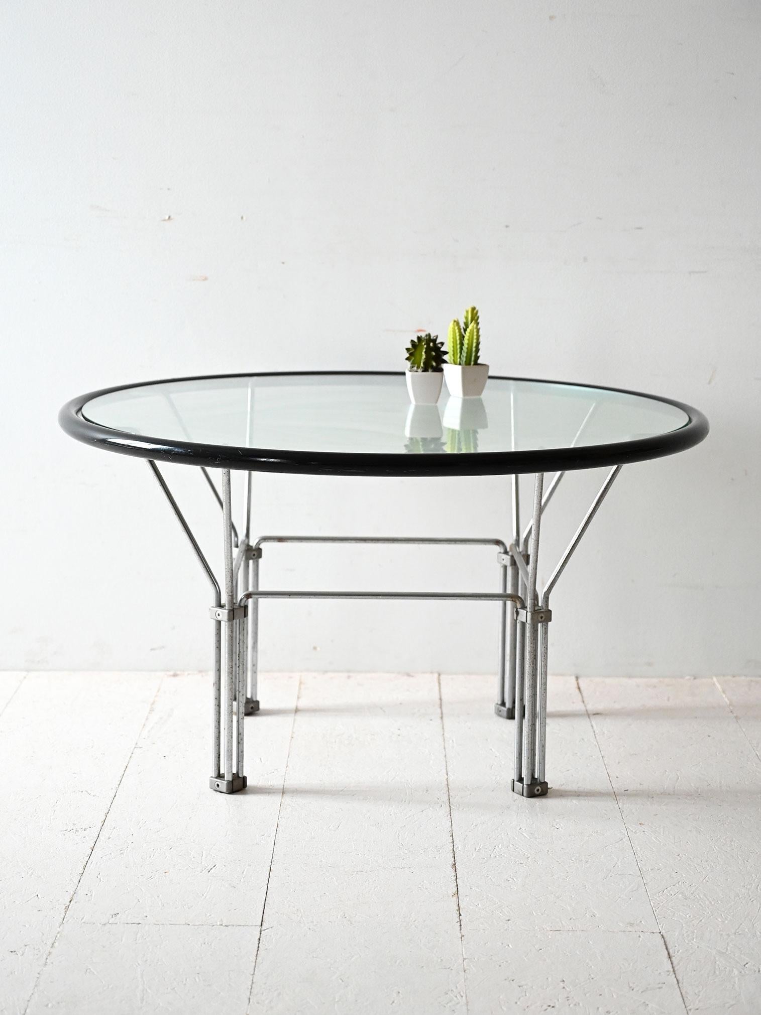 Table basse des années 1970 avec plateau en verre, structure en acier et bord arrondi noir, à caractère industriel et graphique.

Esthétique essentielle et structure géométrique pour cette table basse des années 1970. Le plateau circulaire en verre