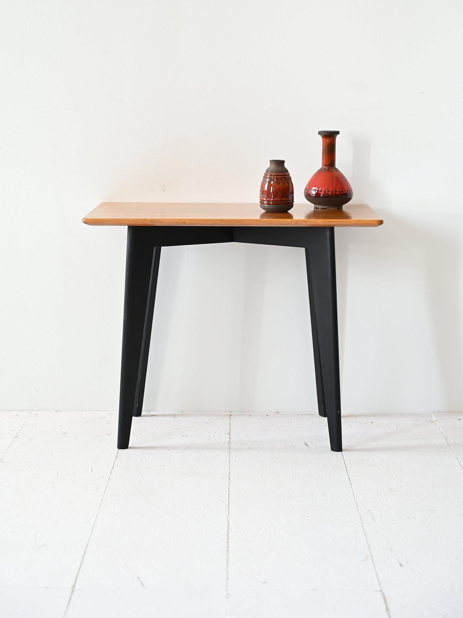 Table basse vintage des années 1960, signée par la société suédoise NK, avec un plateau rectangulaire aux coins arrondis et des pieds en bois peints en noir.

Le plateau de la table, rectangulaire et aux angles légèrement arrondis, présente une