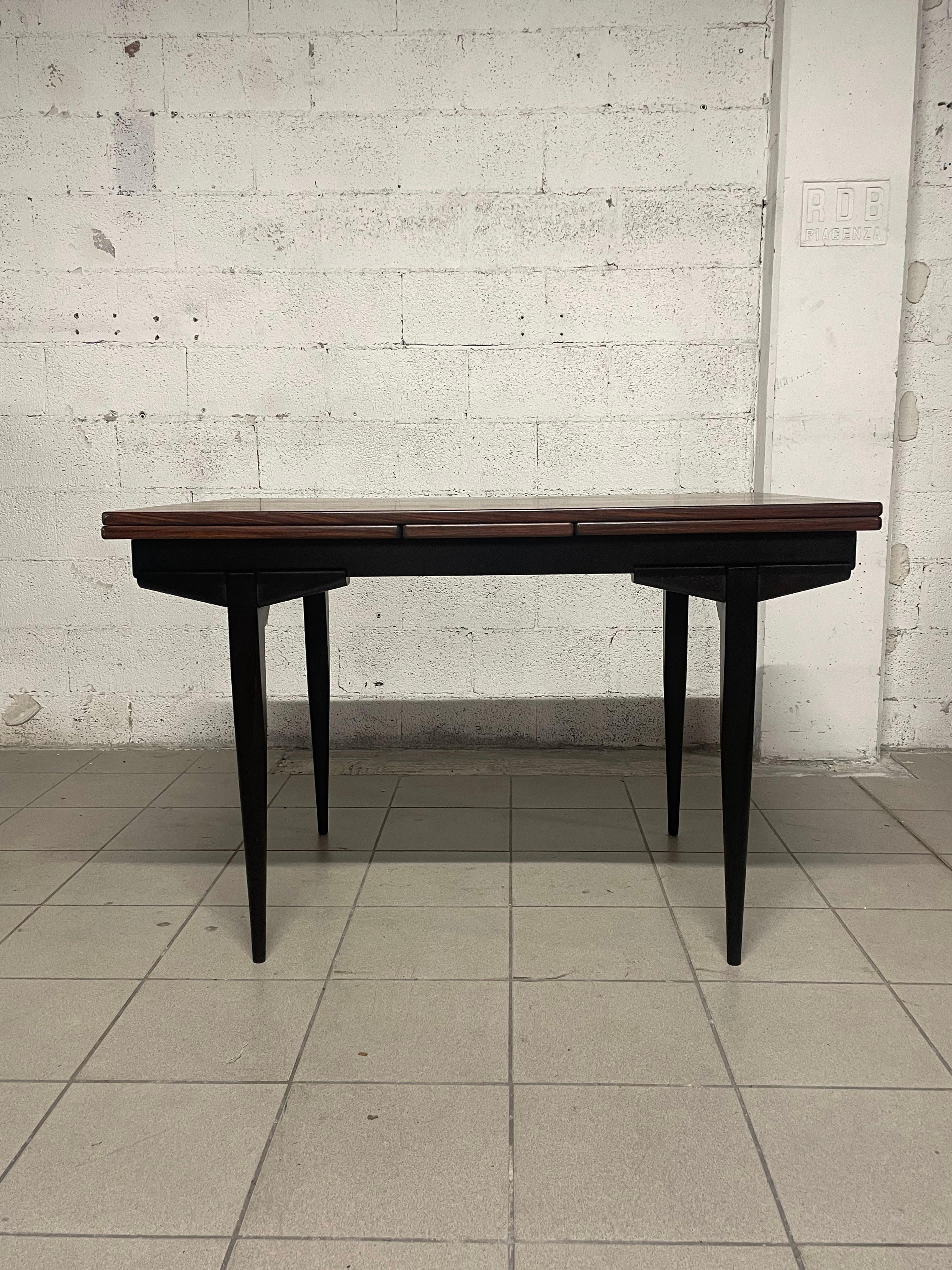 1960s pull-out extension table made of palisander wood with stained wood legs.

With both extensions open, the table reaches a length of 213 cm.
It is perfect for a living area where it can accommodate up to 12 comfortable people if needed.
Also