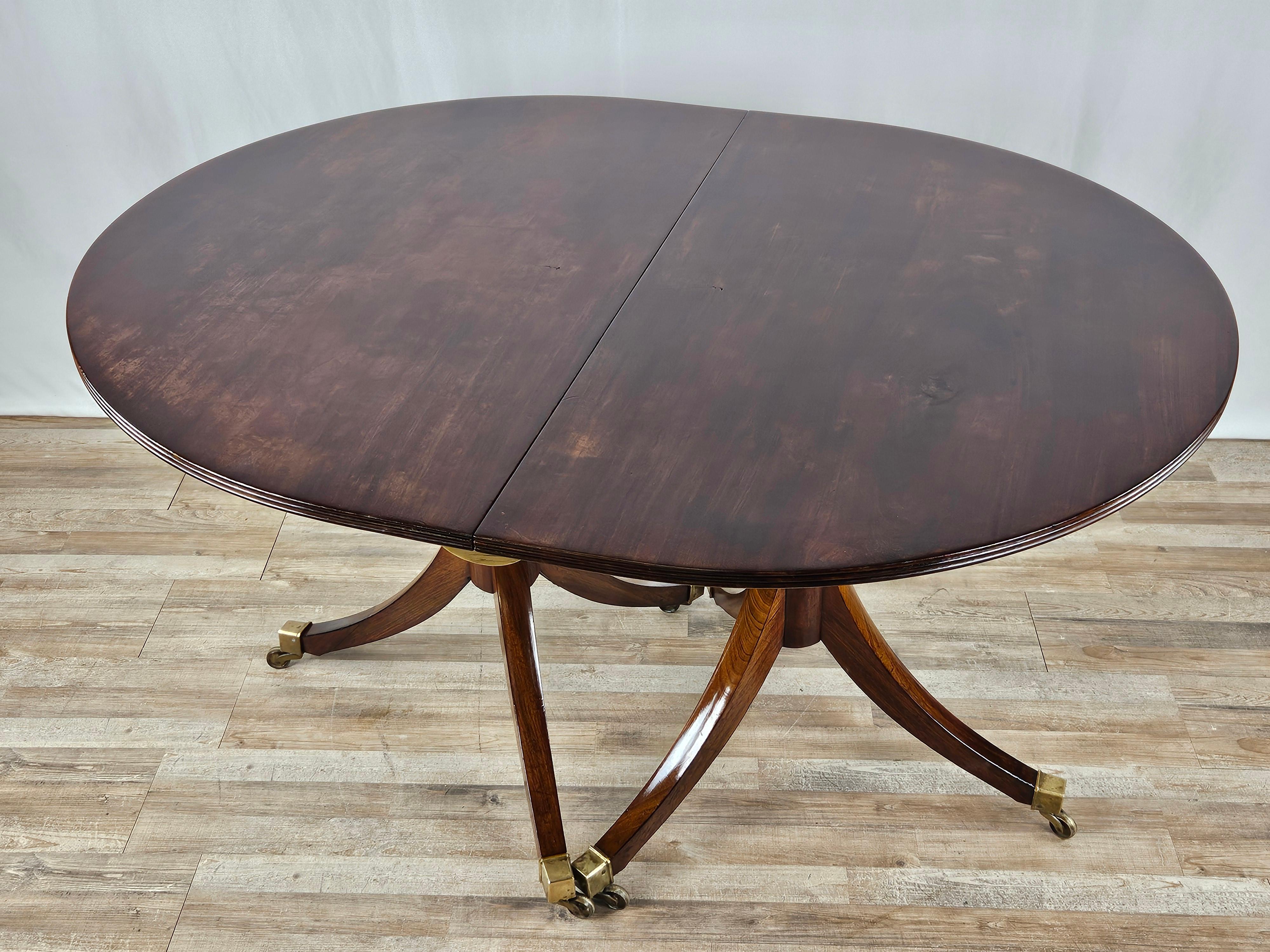 Mahogany English table supported by a double carved and machined frame with brass wheels and finials.

Allowing for different configurations, it can be used as a four-seater table or extended with one or two extensions.

Features two brass 'blocks'