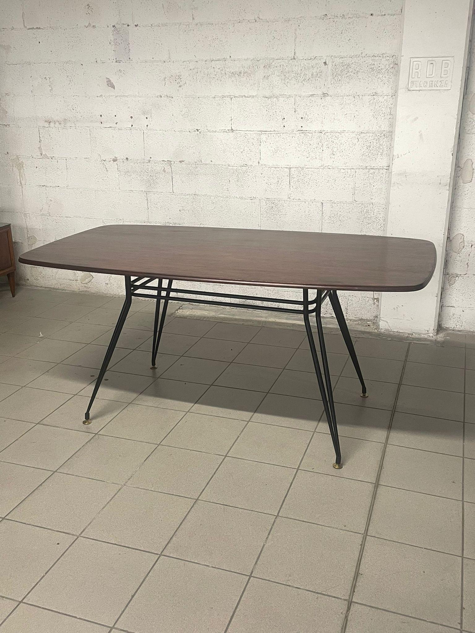 1960s dining table with stained iron frame and rosewood top.

The brass feet are adjustable in height.
At the seating level, the table can accommodate up to a maximum of 8 people.

The table is in good condition, the top may have some surface marks
