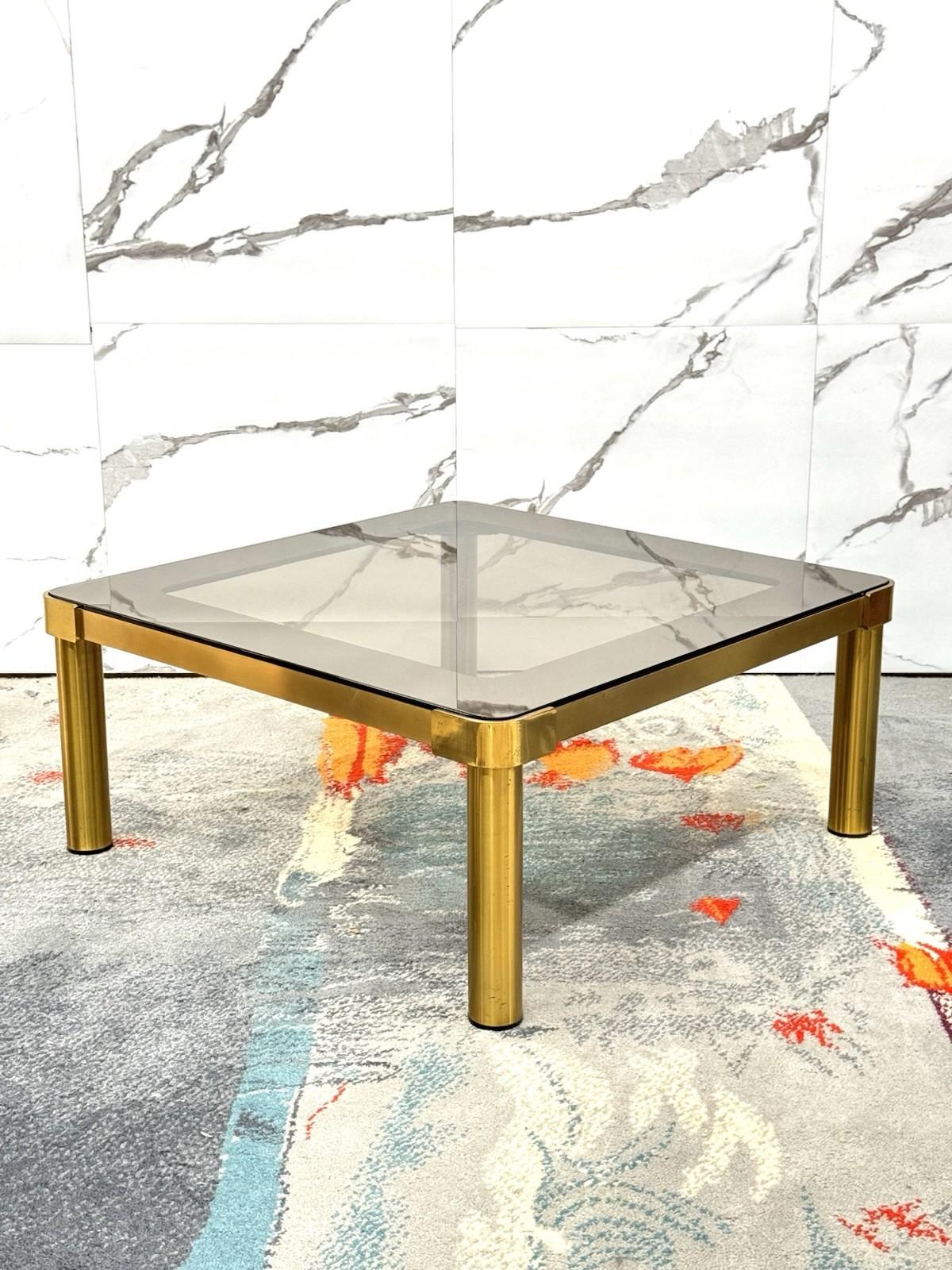 Tavolo Basso In Ottone e Vetro Fumé – Hollywood Regency, Anni ’70


Elegante tavolo basso da salotto in perfetto stile Hollywood Regency, databile agli anni ’70. La struttura è in ottone dorato lucido, con gambe cilindriche robuste e dettagli