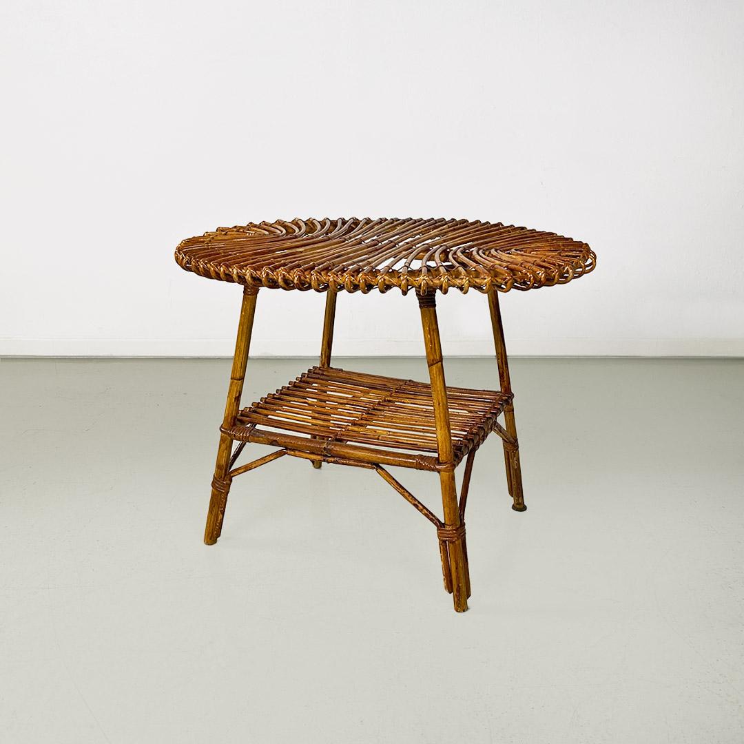 Table basse d'extérieur avec structure en rotin, plateau ovale et tablette de rangement inférieure, tous deux réalisés en bandes de rotin avec joints sur les profils et quatre pieds dans le même matériau.
c. 1960
Bon état, signes du temps. Non