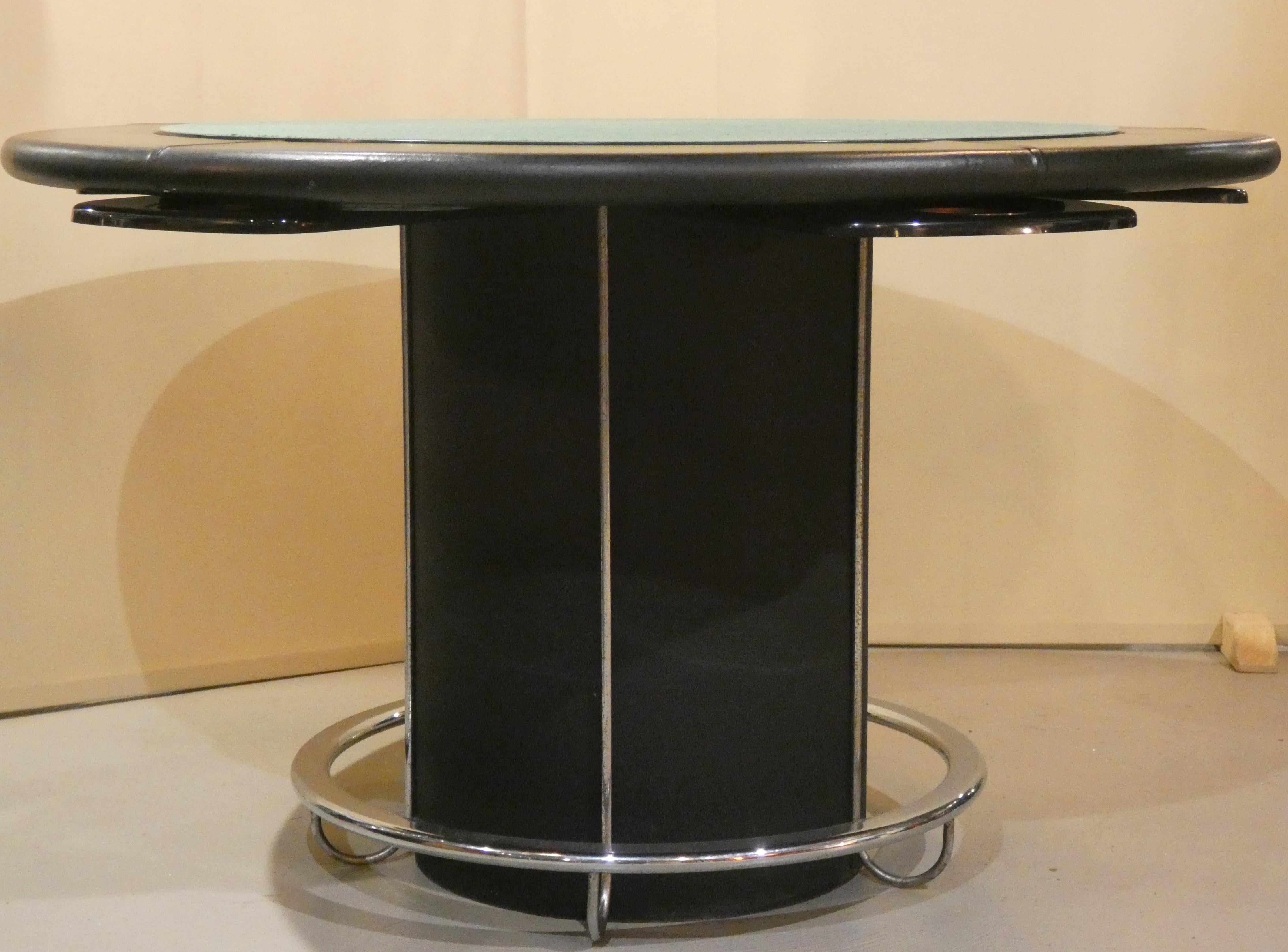Table de jeu bordée de cuir, avec corps en acier peint en noir et pied de table en acier chromé. Au centre de la table se trouve un panneau double face représentant le tapis vert et l'échiquier. La table est conçue pour cinq personnes, et à côté de