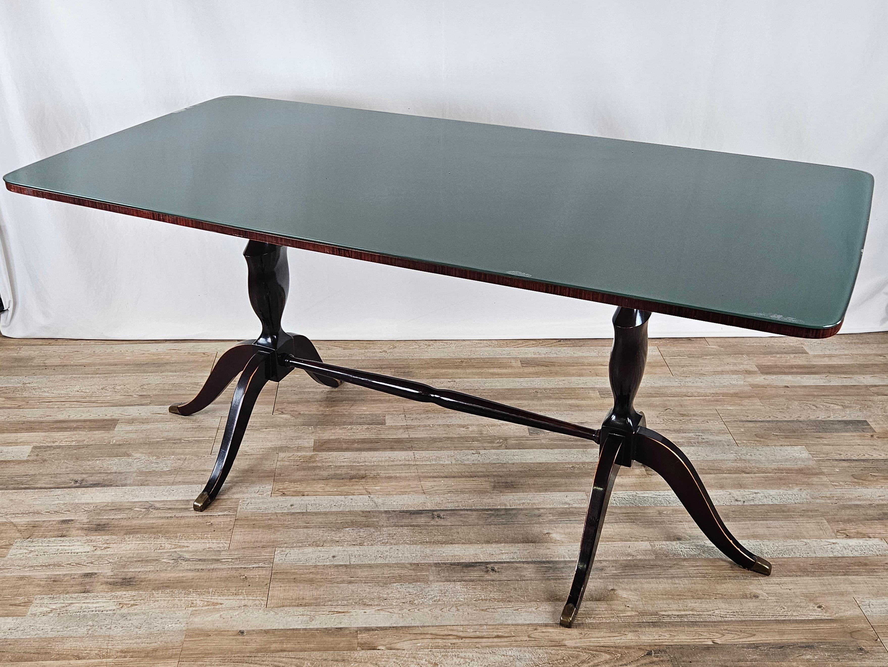 Mid-20th-century Italian dining table with a wooden frame decorated with brass foot finials and a beautiful green glass top.

Perfect in a living room or kitchen with a vintage and modern flavor, it can be combined with a variety of seating