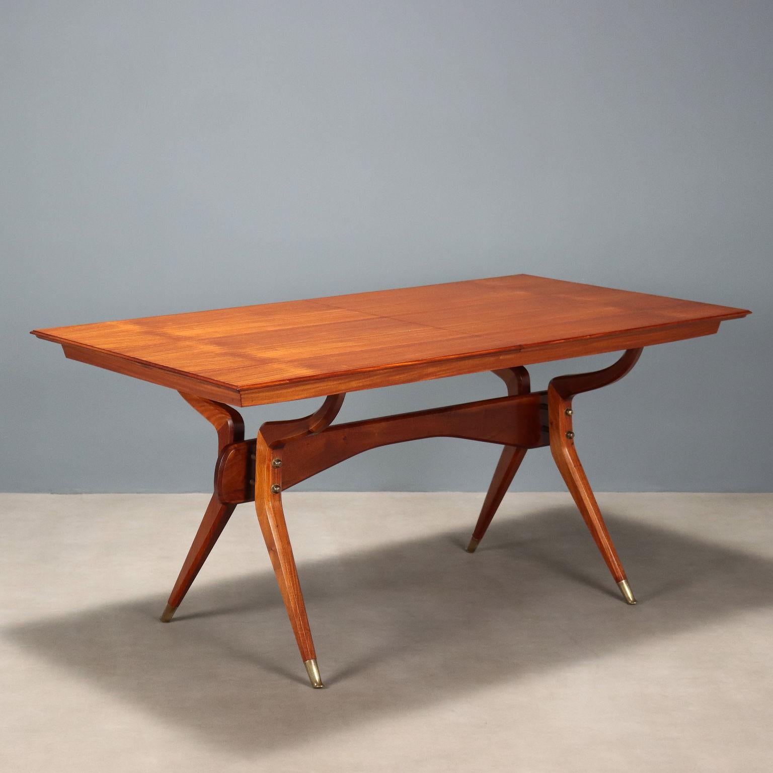 Elégante table de salle à manger en bois plaqué acajou avec pied en bois courbé avec détails en laiton ainsi que les pieds ; plateau de forme rectangulaire extensible. Meubles restaurés dans nos ateliers, rallonge électrique absente.