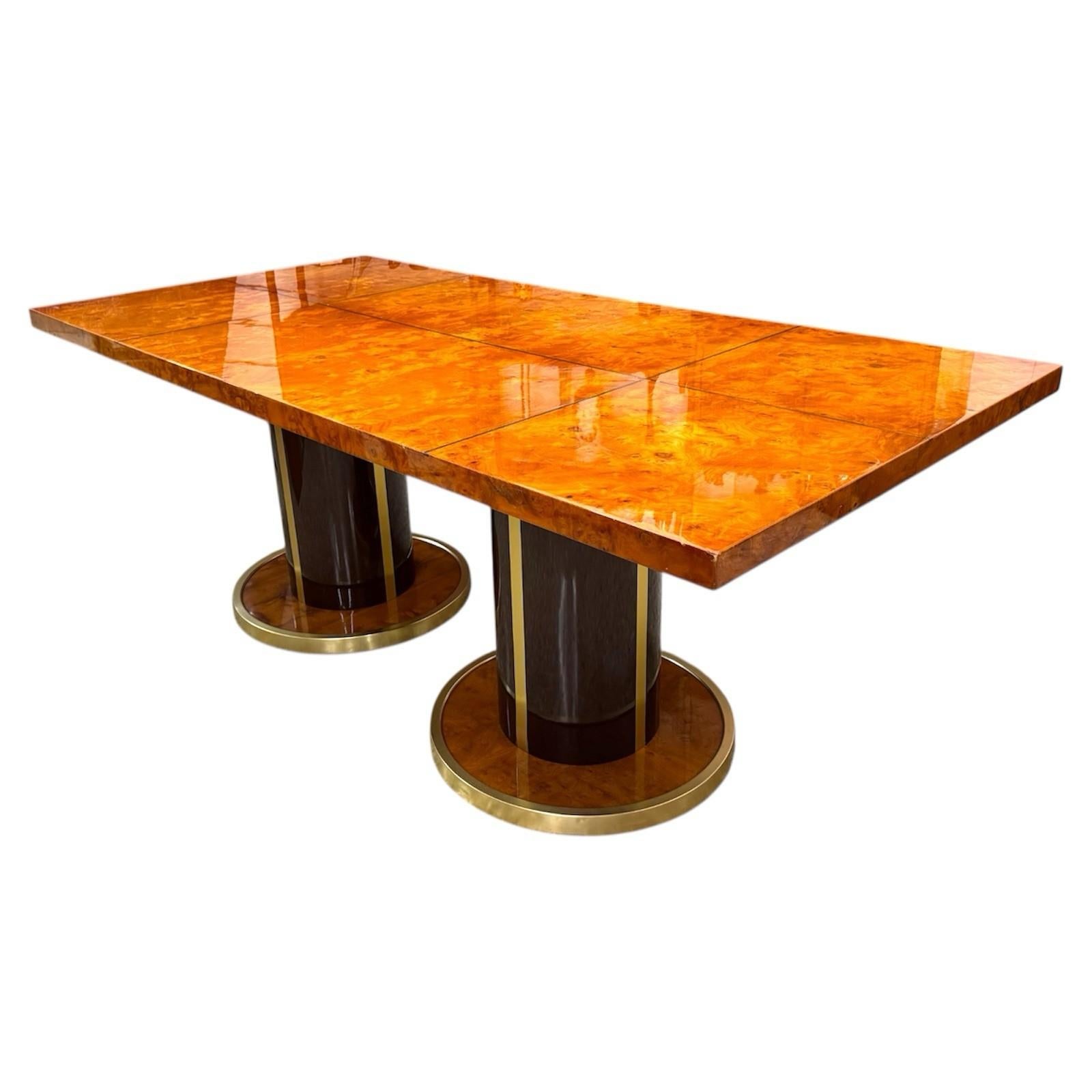 Maestoso tavolo da pranzo risalente agli anni ’70, realizzato con materiali pregiati e un design tipico del modernariato di alta gamma. Il piano rettangolare in radica lucida presenta una finitura a specchio che esalta le venature naturali e calde