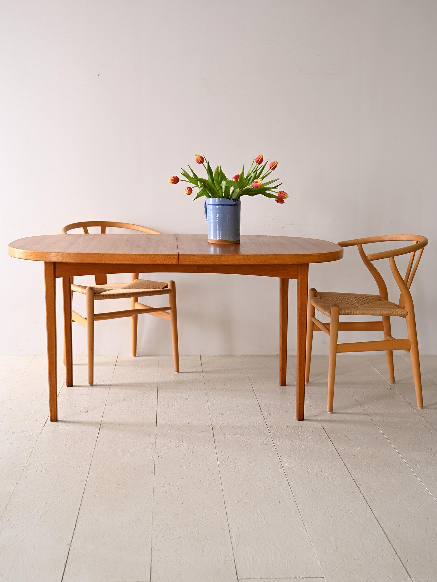Vintage dining table with additional board. 

A piece of unquestionable beauty that stands out for its minimalist lines and the bold tone of teak wood. The top can be extended as needed by the addition of the center axis, a feature that reflects the