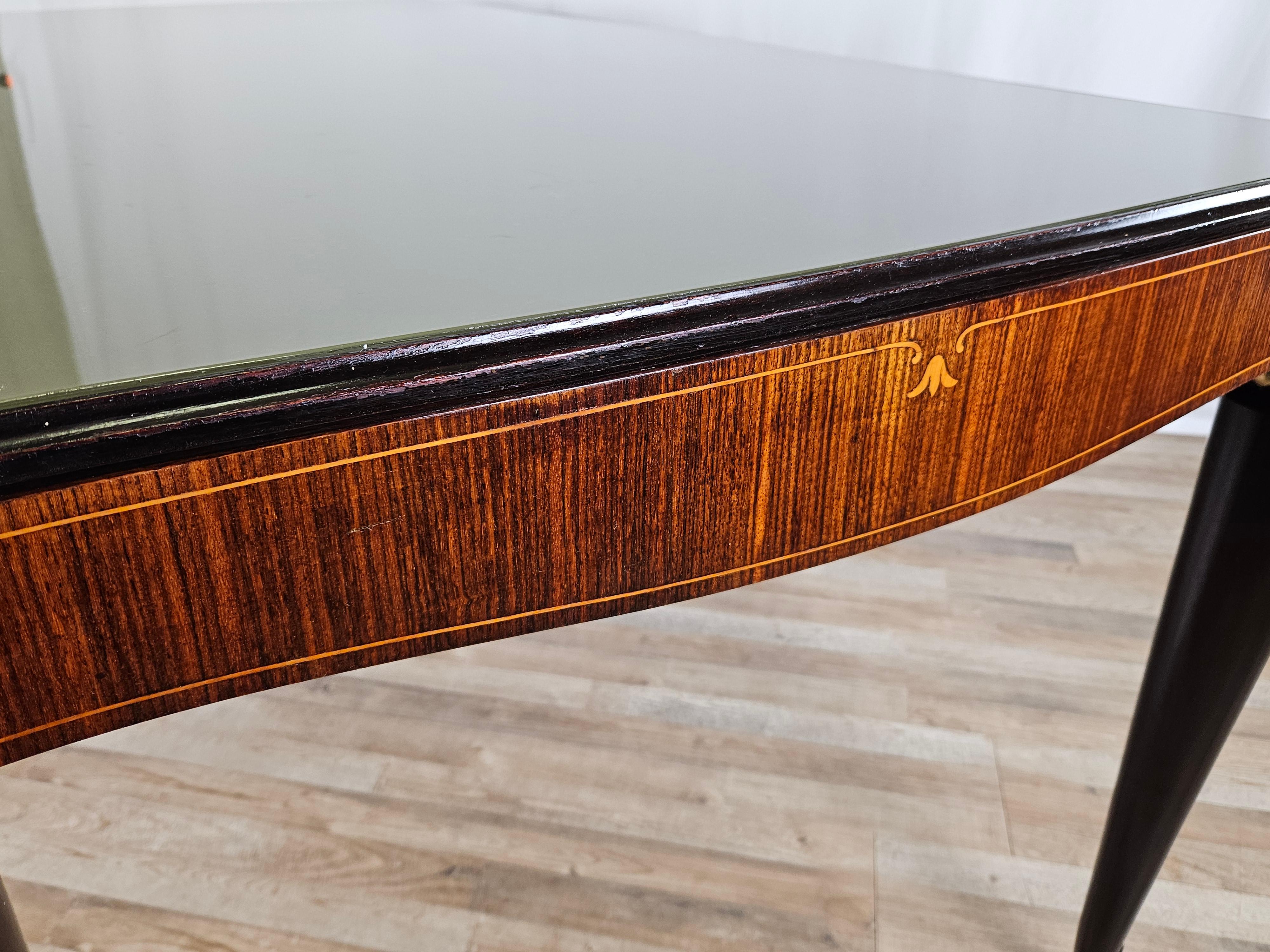 Elegant mid-20th-century mahogany dining table with ebonized profile and legs and brass end covers.

The table features a distinctive glass top with a shaped edge and contrasting shade to the frame to create a beautiful effect match any kind of