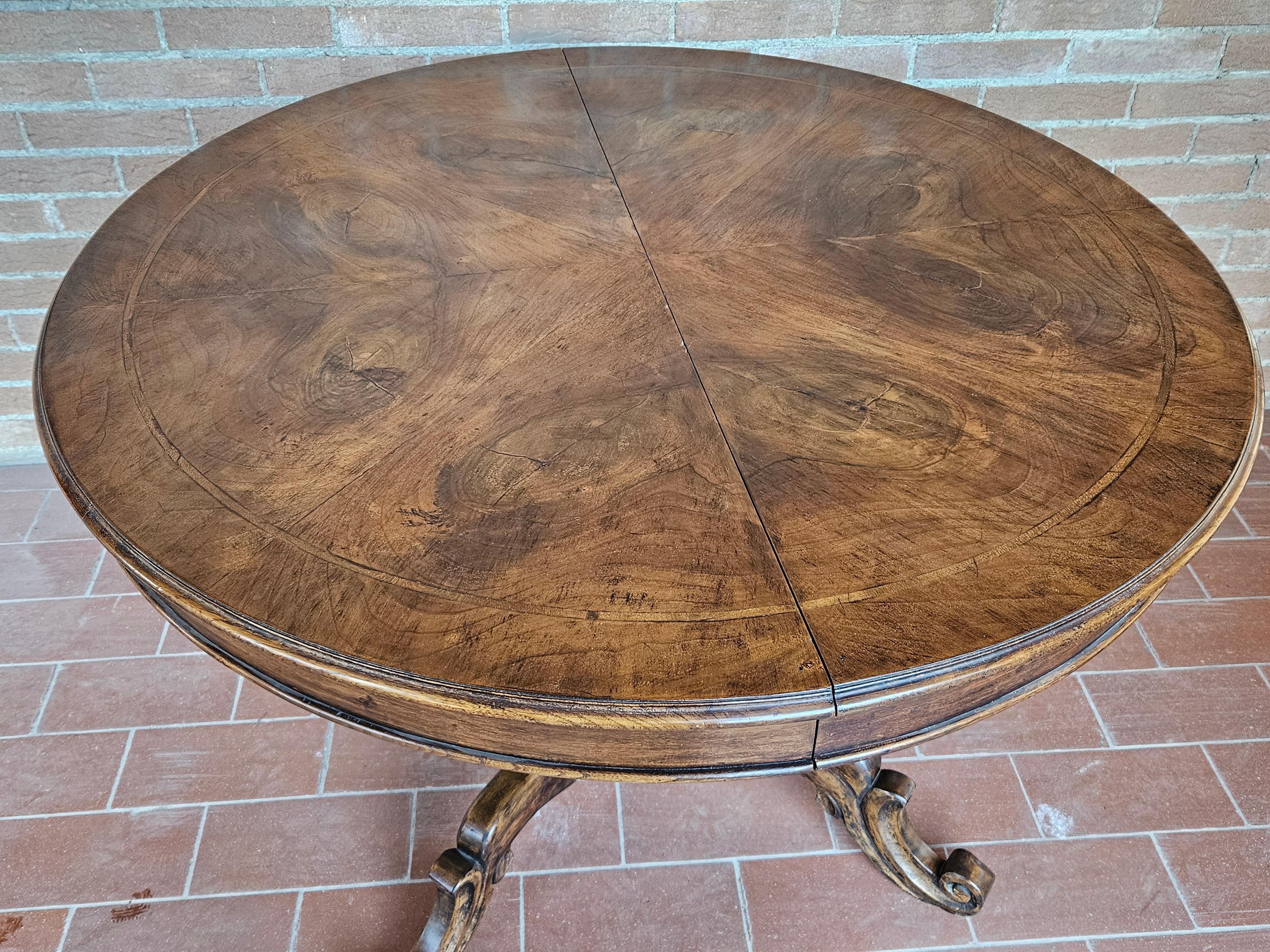Elegant dining table from the early 1930s, Italian production of high quality and workmanship.

It features a walnut frame and a top covered in walnut burl, note the detailed and rich carvings and decorations along the base and perimeter.

The table