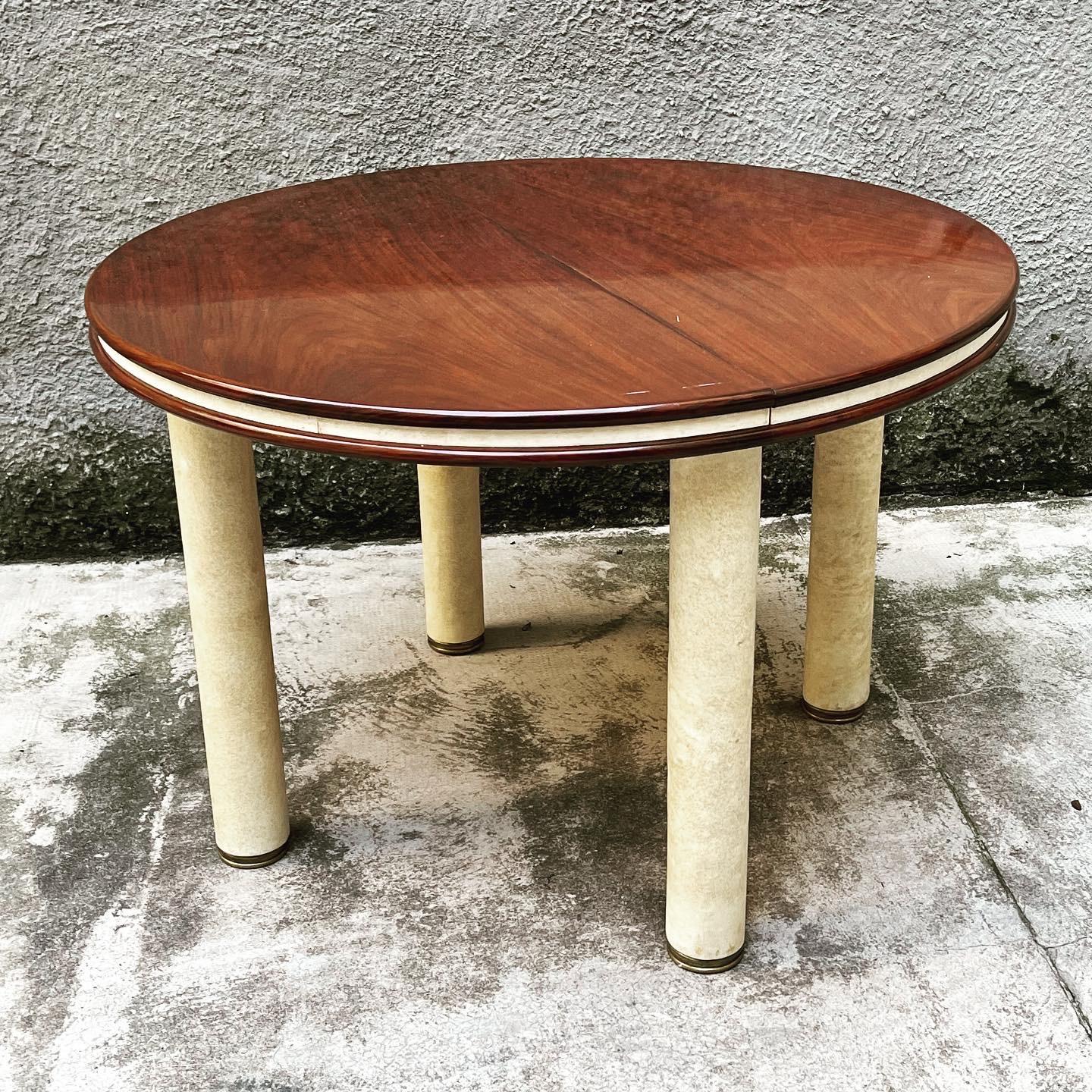 This visually striking, elegant and functional Italian table has the ability to extend to become oval (no extension). Made circa 1960s. Its two main contrasting materials only teak and light vellum. The four sturdy covered legs end in 4 large brass