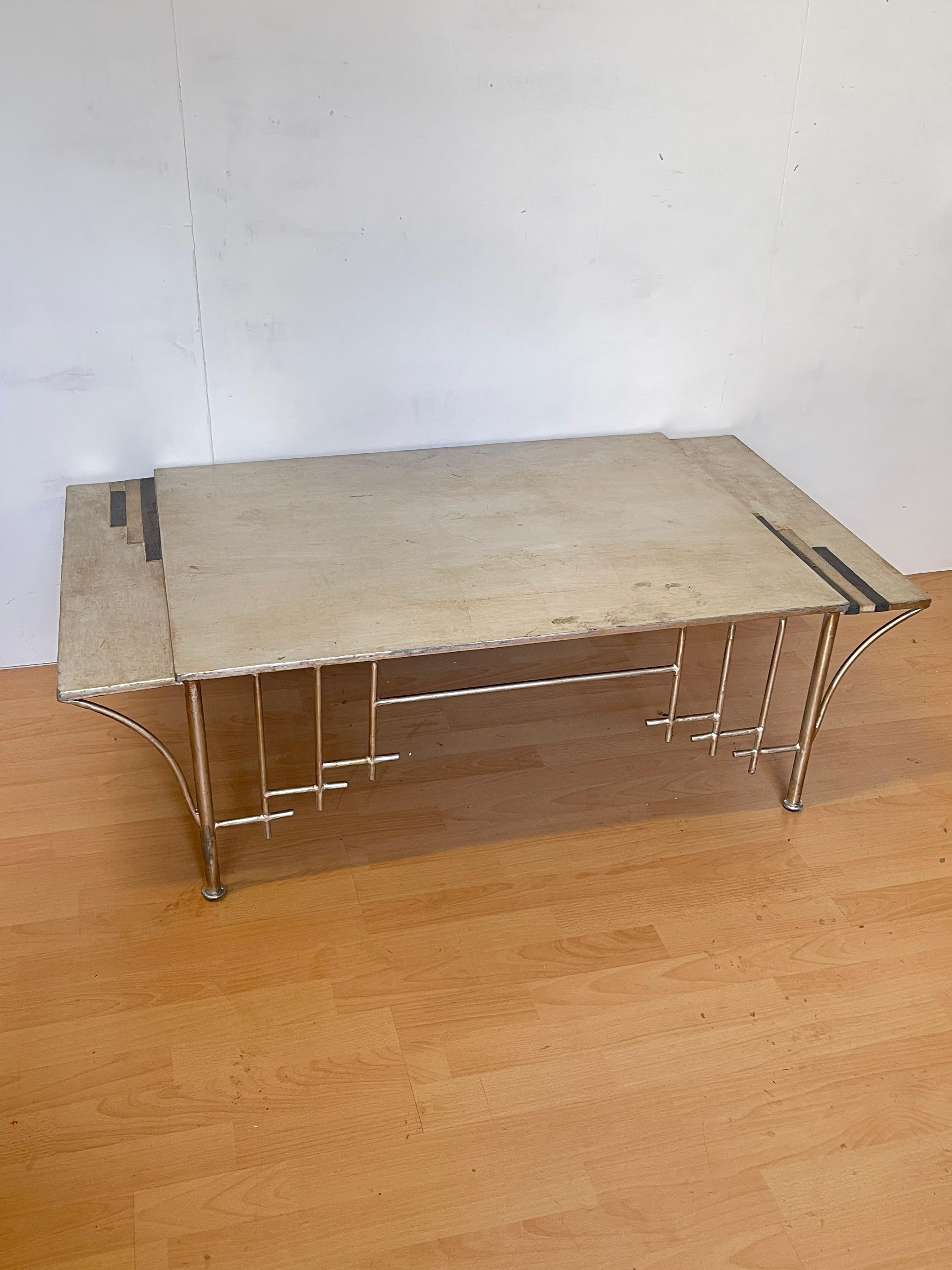 La table de salon allie élégance et solidité grâce à la combinaison d'une surface en bois clair et d'un cadre en acier inoxydable argenté. Les lignes géométriques, épurées et originales font de cette table un véritable élément de design, parfait