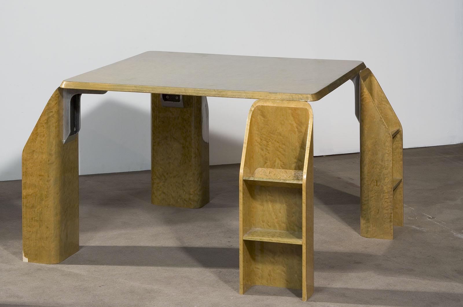 Mesa diseñada por Giovanni Offredi para Saporiti en 1970.
El esbelto tablero de la mesa descansa sobre cuatro patas de apoyo más anchas, cada una de las cuales tiene dos compartimentos de almacenamiento, girados en cada dirección. Hecho enteramente