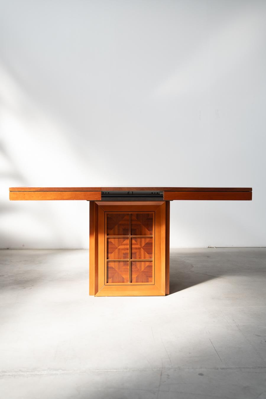 Tisch aus Kirschbaumfurnier, mit Verlängerung, 1970/80er Jahre
Tisch mit geometrischen Schnitzereien auf zentralem Sockel
                                                 Abmessungen GESCHLOSSEN: H78 X B115 X T115 - KG50
            Abmessungen