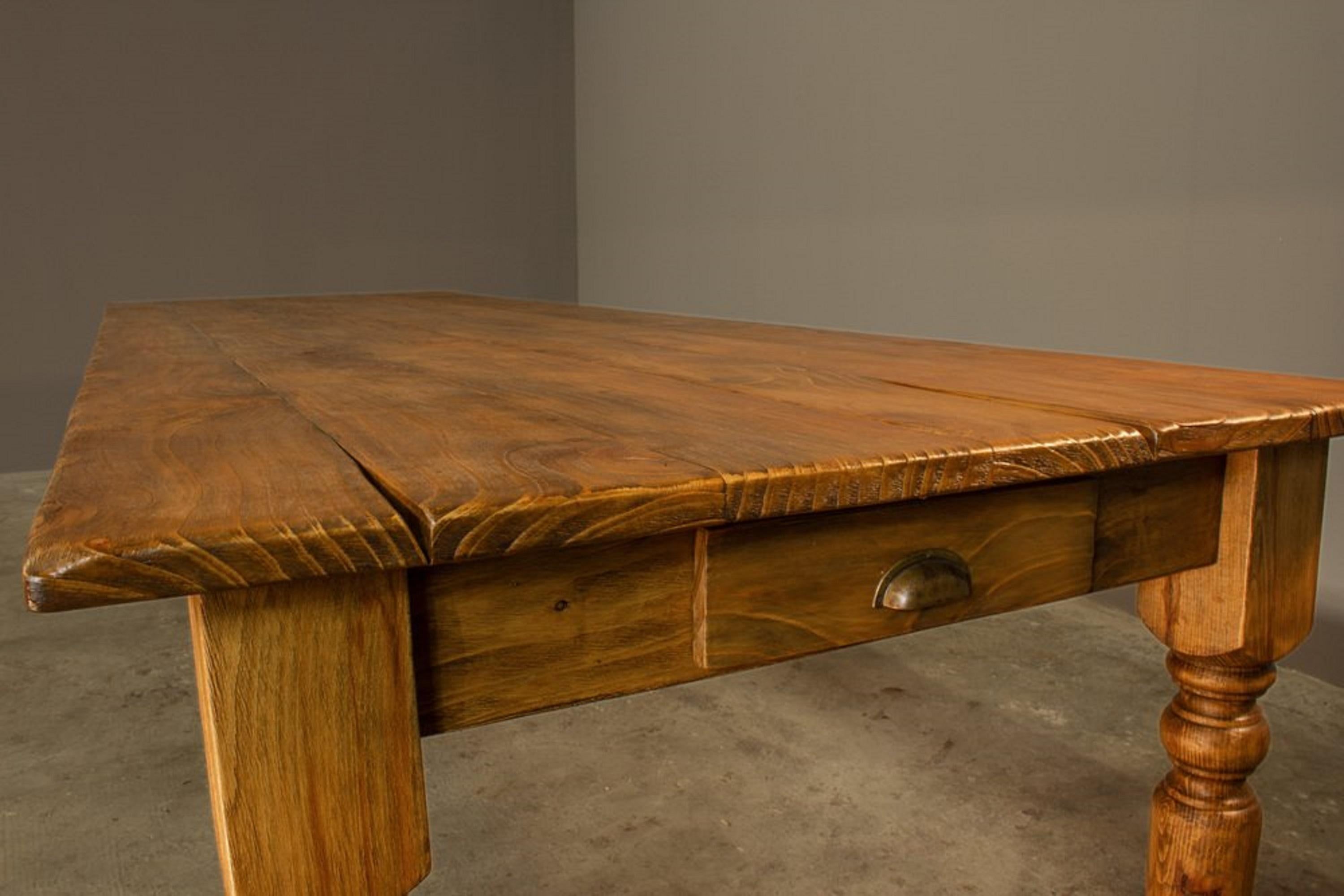 Une magnifique table artisanale entièrement fabriquée en bois de cèdre massif, caractérisée par une structure imposante et un design rustique intemporel. Le plateau, composé de planches épaisses au grain naturel clair et aux nœuds authentiques, est