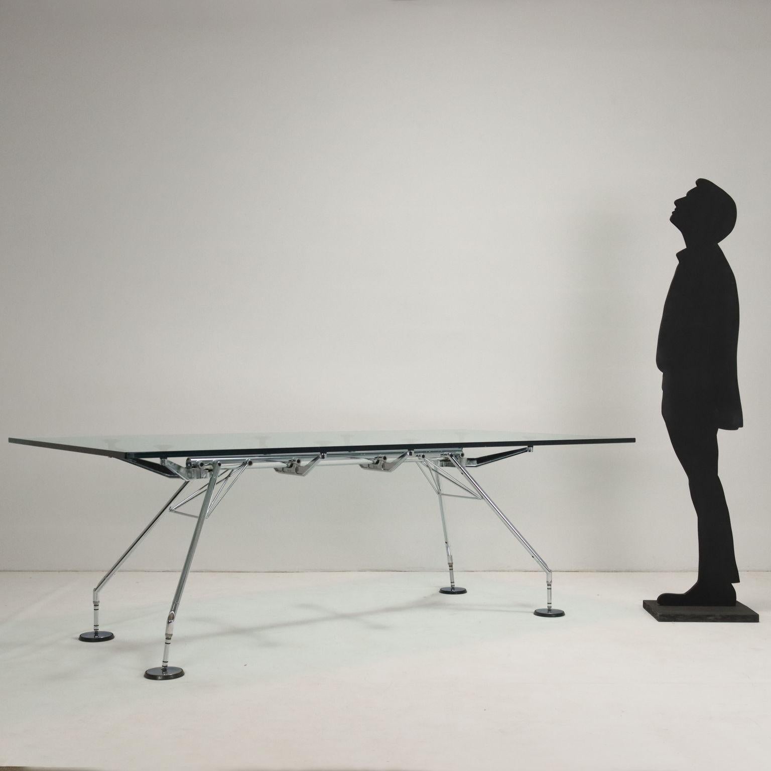 Tavolo con base in metallo cromato e piano in vetro; il tavolo Nomos firmato da Norman Foster è stato vincitore del prestigioso 'Compasso d'Oro' nel 1987, è un tavolo che colpisce per la sua struttura unica e dall'estetica zoomorfica, il solido