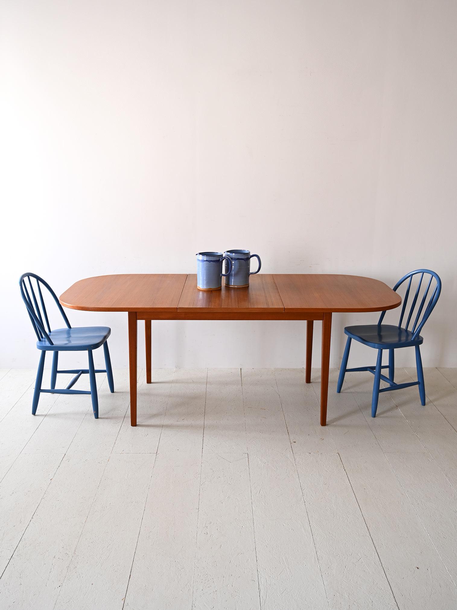 Vintage dining table with additional board.

A piece of unquestionable beauty that stands out for its minimalist lines and the bold tone of teak wood. 
The top can be extended as needed by the addition of the center axis, a feature that reflects the